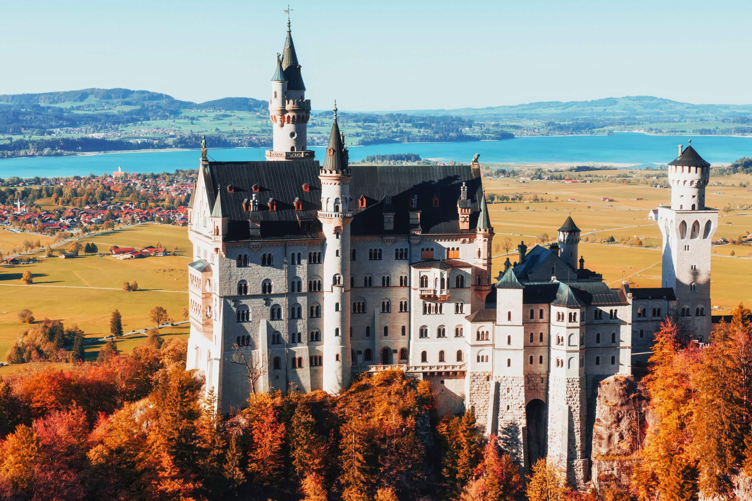 Neuschwanstein Castle: via Adobe Stock Neuschwanstein Castle viewed from the Marienbrücke in autumn, with Lake Forggensee and the Bavarian plain behind