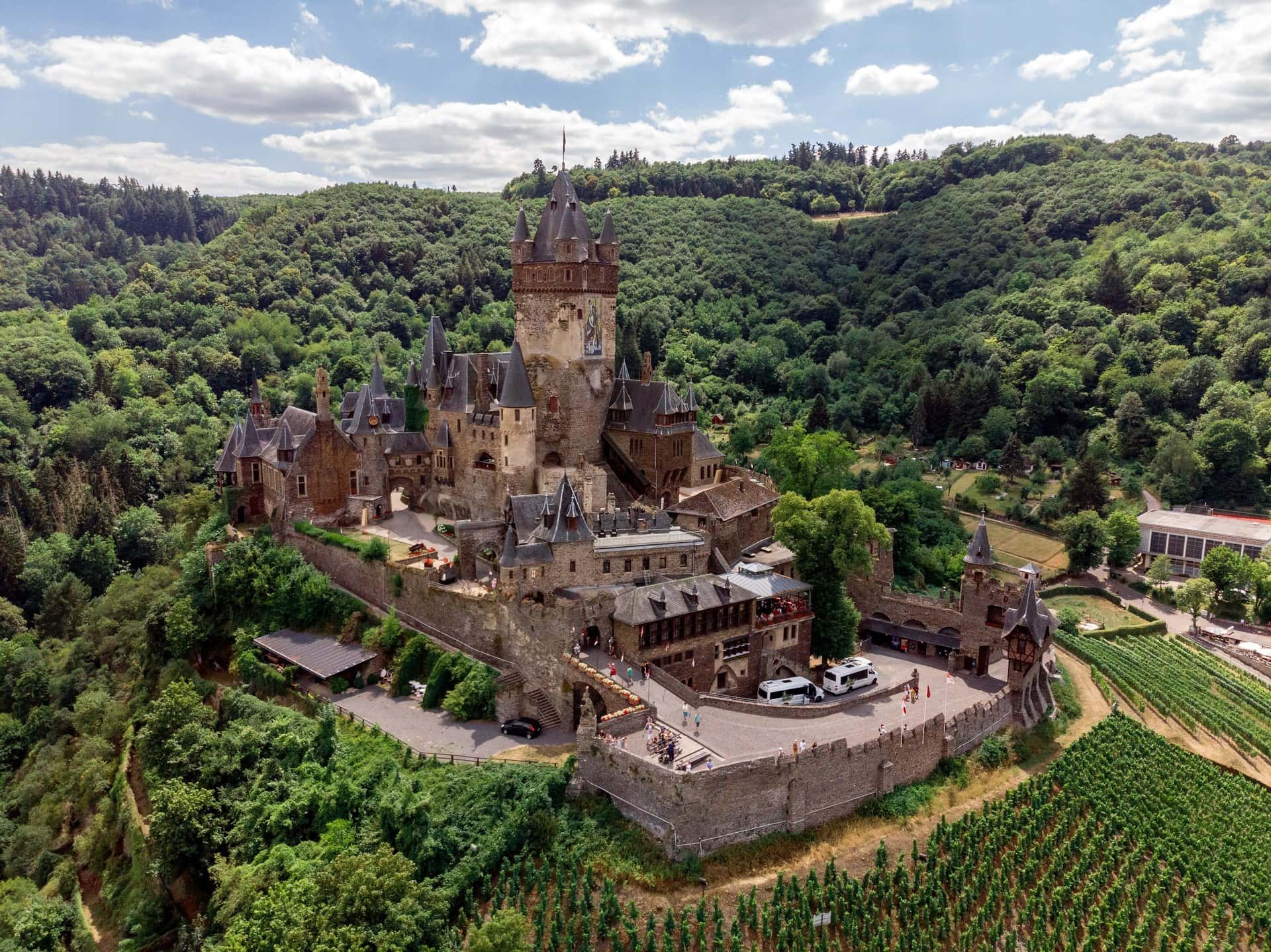 Aerial view of Reichsburg Cochem on its conical hill surrounded by vineyard terraces and the Moselle river