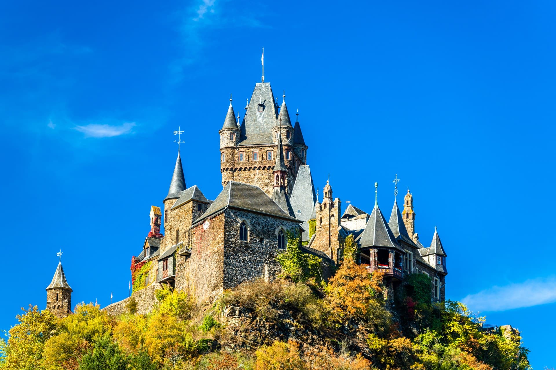 Reichsburg Cochem in autumn with the Bergfried keep and Neo-Gothic tourelles against a deep blue sky