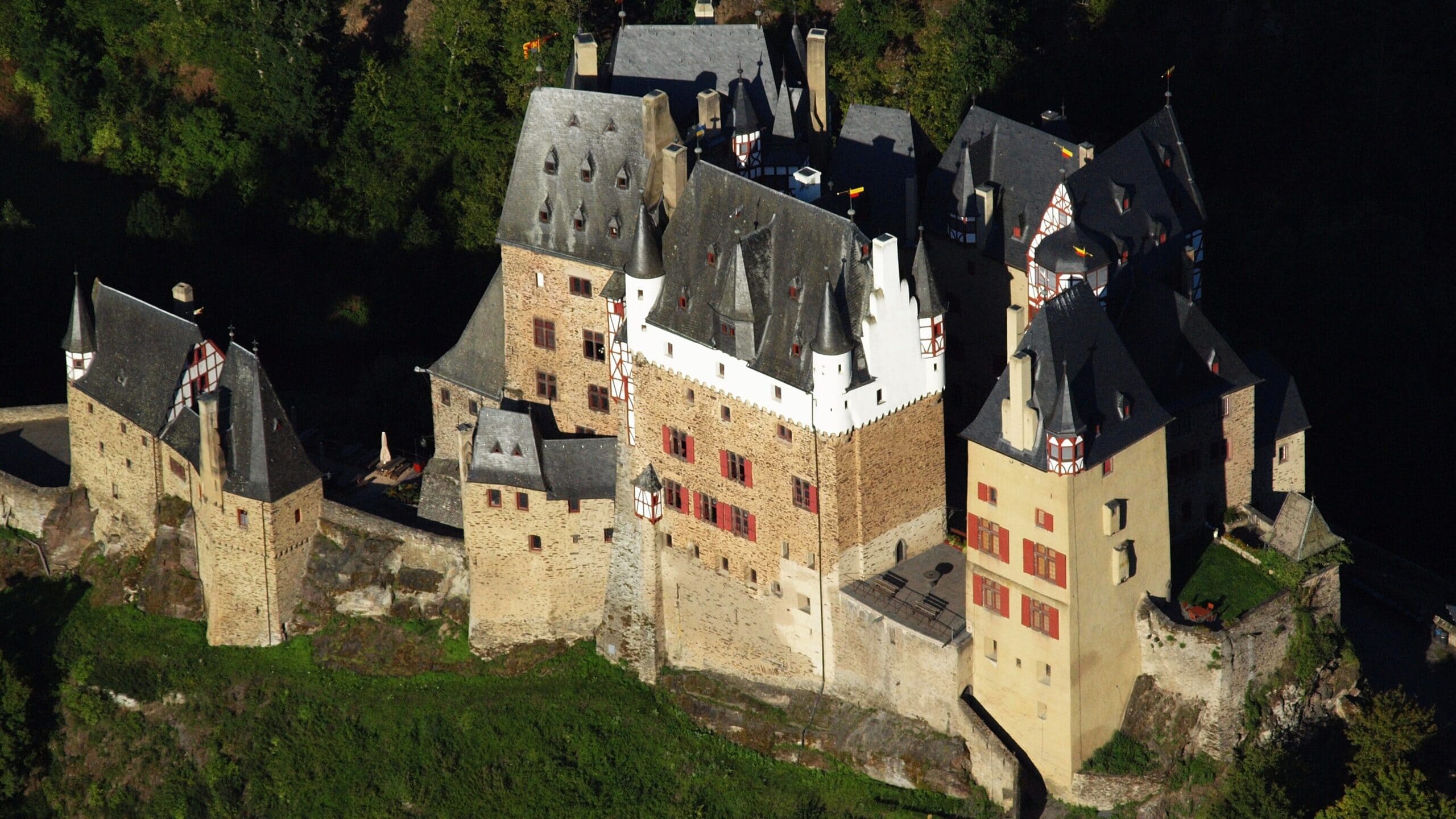 Eltz Castle 3 Close aerial view of the residential cluster at Burg Eltz showing the white-rendered Kempenich tower at the center and the half-timbered upper stories of the Rodendorf and Rübenach wings
