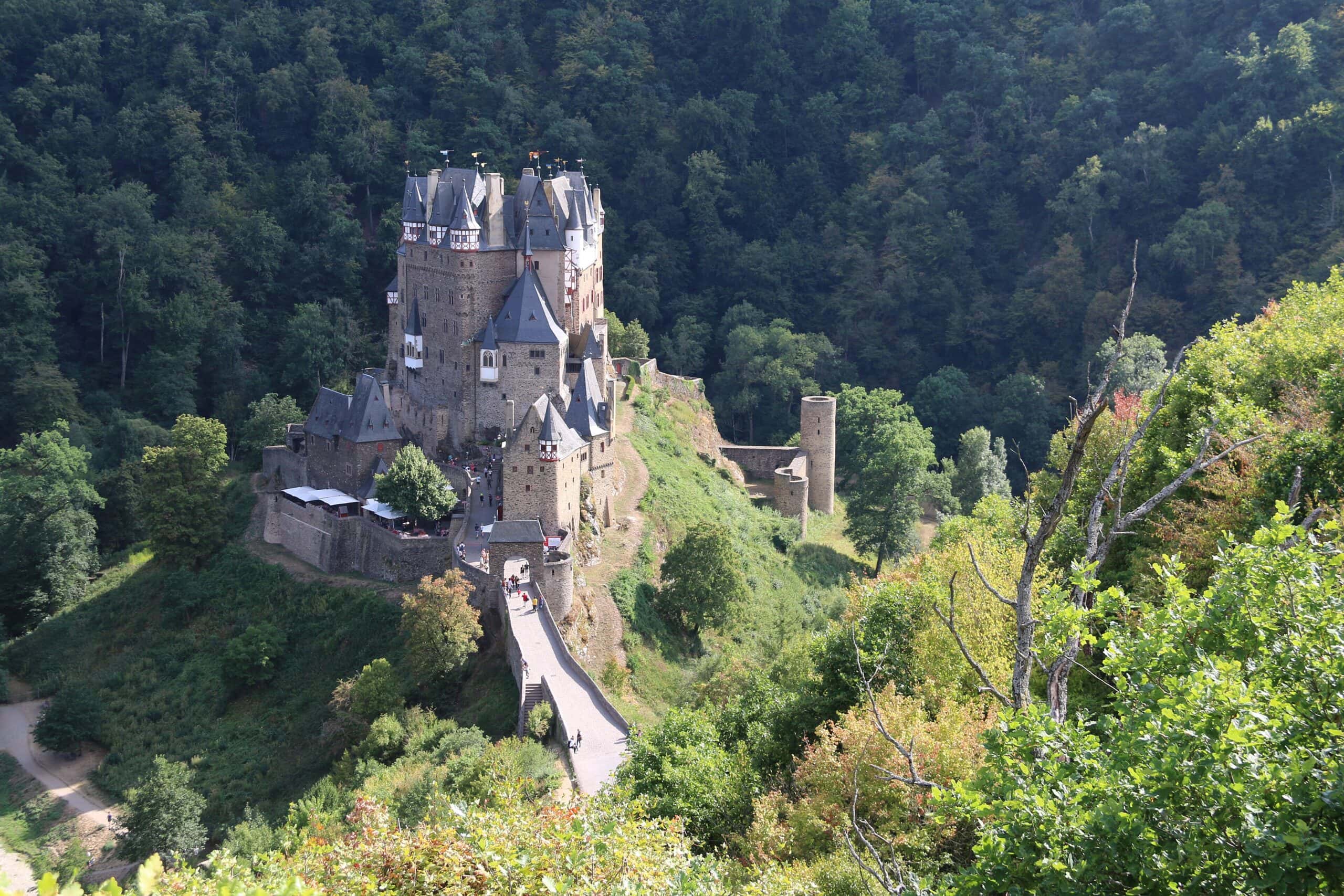 Eltz Castle 1 Burg Eltz on its rock spur viewed from the elevated trail above the Elzbach valley, with the round tower of the Trutzeltz siege castle ruin visible on the wooded ridge to the right
