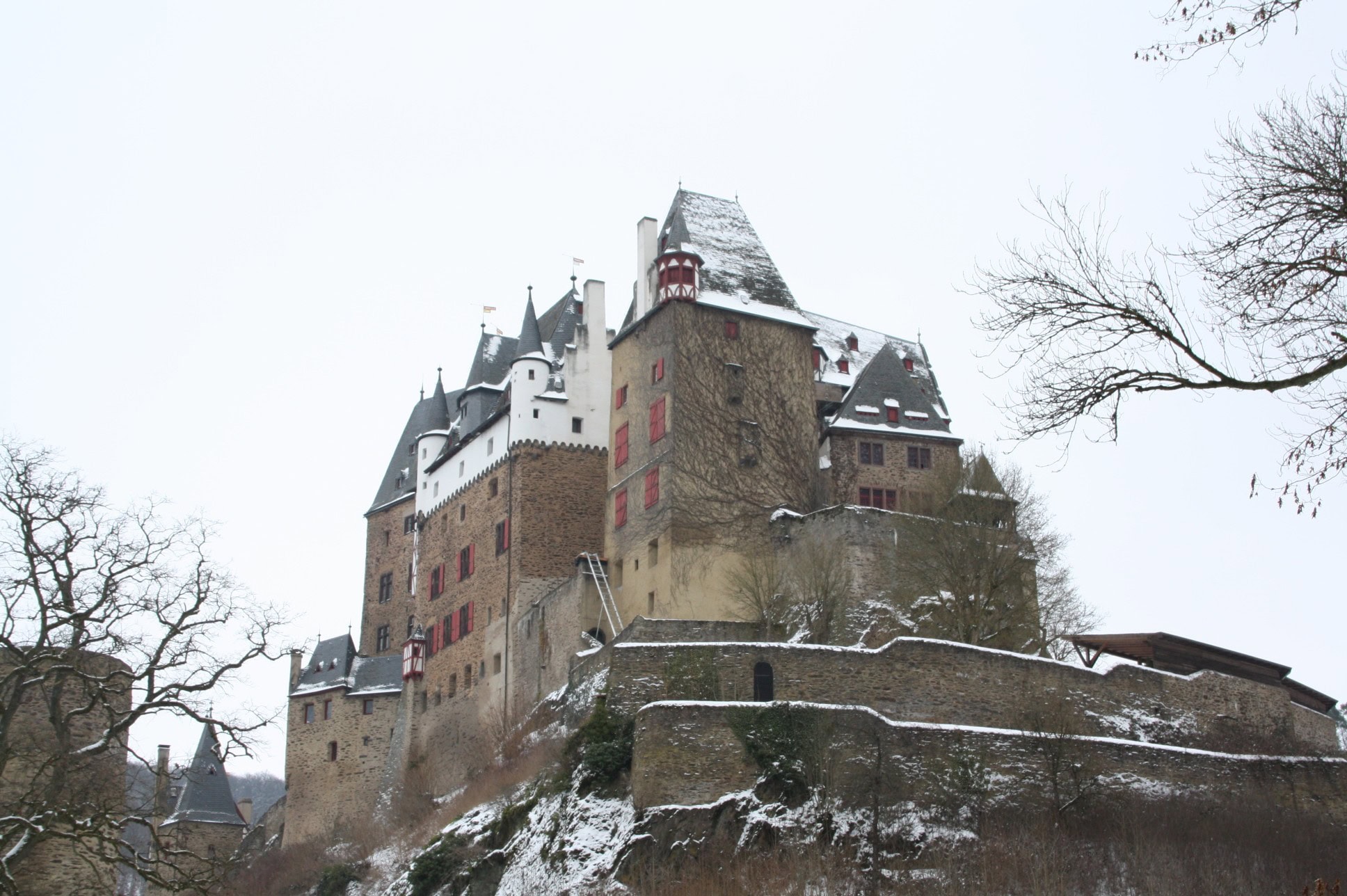 Eltz Castle 4 Burg Eltz viewed in winter from the southwest with snow on the slate roofs and the bare trees revealing the rock spur and curtain wall around the castle