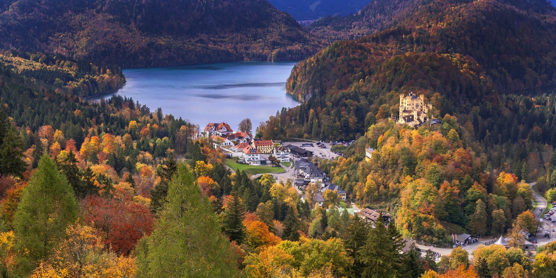 The 19th-Century Romantic Revival of German Castles 5 Schloss Hohenschwangau in autumn light, perched on its hillside above the Alpsee, with the Bavarian Alps in the background.