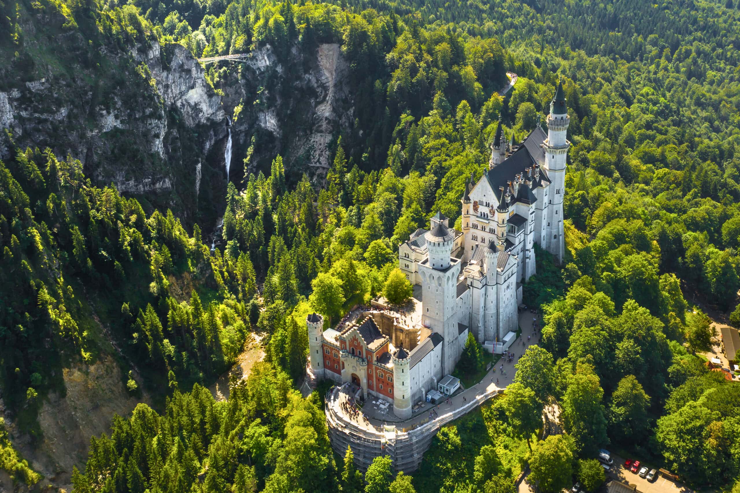 The 19th-Century Romantic Revival of German Castles 11 Aerial view of Neuschwanstein in summer, with the Pöllat gorge and its waterfall to one side and the Bavarian Alps in the distance.