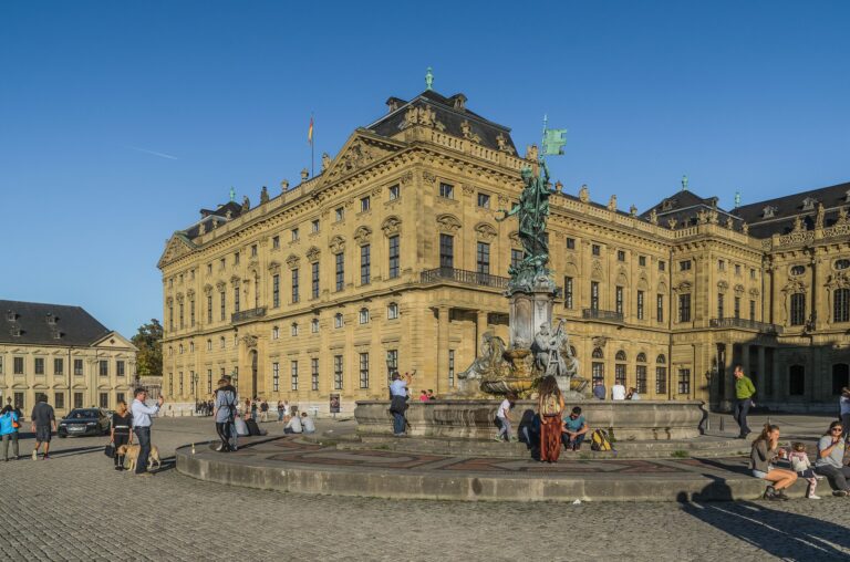Würzburg Residence 4 The west façade of the Würzburg Residence, almost 170 meters of pale sandstone, viewed at three-quarter angle from the Residenzplatz with the Frankoniabrunnen in the foreground.