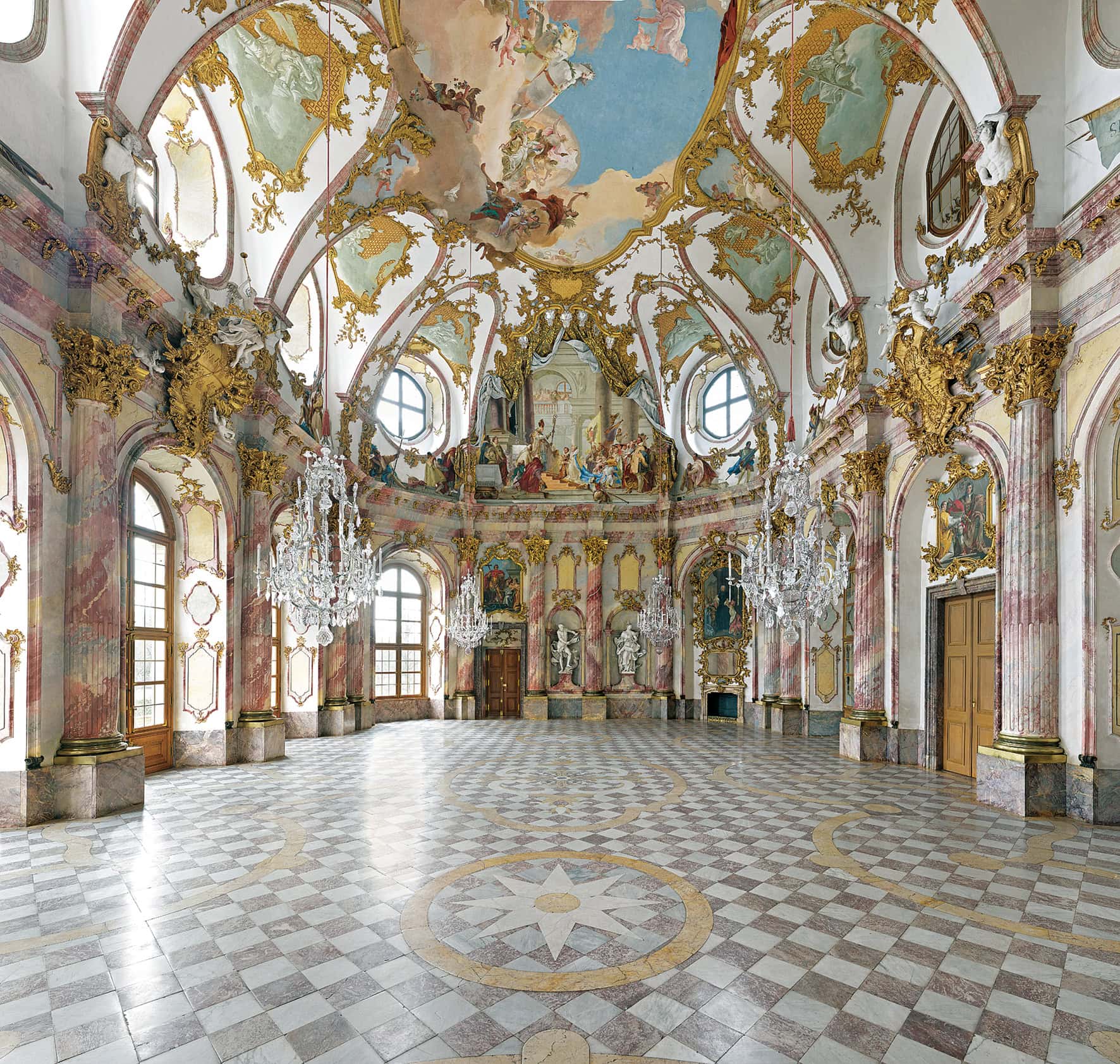 Würzburg Residence 4 Interior of the Kaisersaal at the Würzburg Residence with marbled half-columns, crystal chandeliers, checkered marble floor, and the central Tiepolo ceiling fresco visible above.