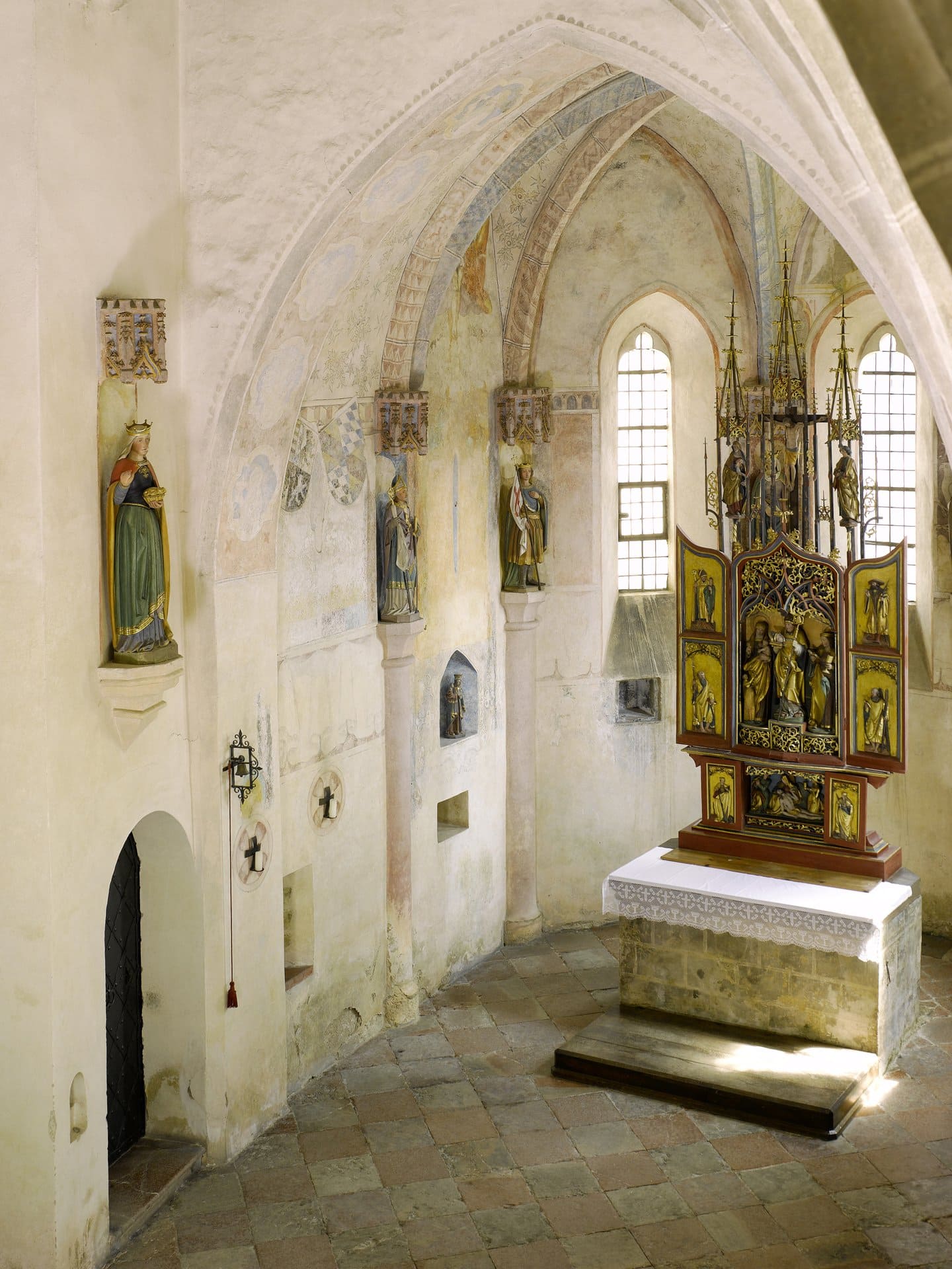 Burghausen Castle 2 Interior of the inner Burgkapelle of St. Elisabeth at Burghausen Castle, with painted Gothic ribbed vaulting overhead, a polychrome statue of Saint Elisabeth in a wall niche on the left, three painted niches with statues of saints along the wall, and a late-Gothic winged altarpiece on the right.