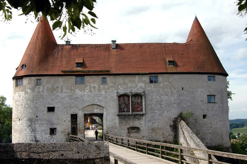 Burghausen Castle 3 The Georgstor of Burghausen Castle, viewed from the bridge approach, showing the late-Gothic gateway between two flanking towers with conical red tile roofs and the painted Bavarian-Polish coat of arms above the arch.