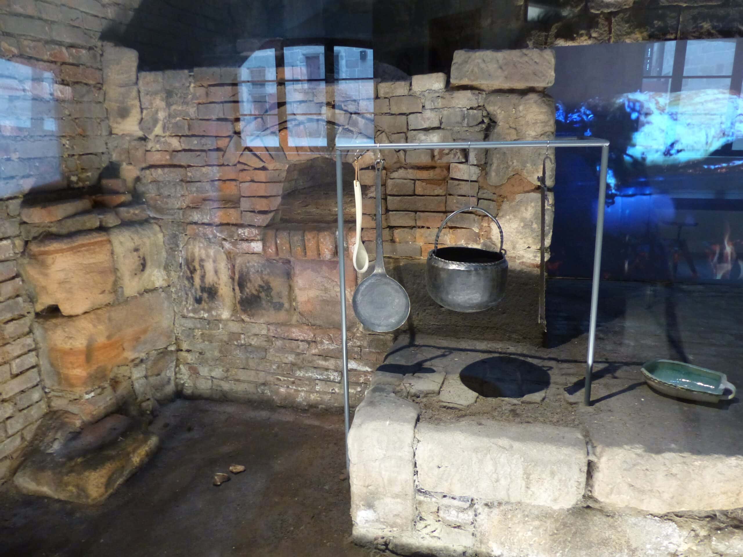 Cadolzburg Castle 6 Reconstructed medieval kitchen at Cadolzburg with excavated stone hearth, bread oven, and exposed sandstone walls under arched vaulting