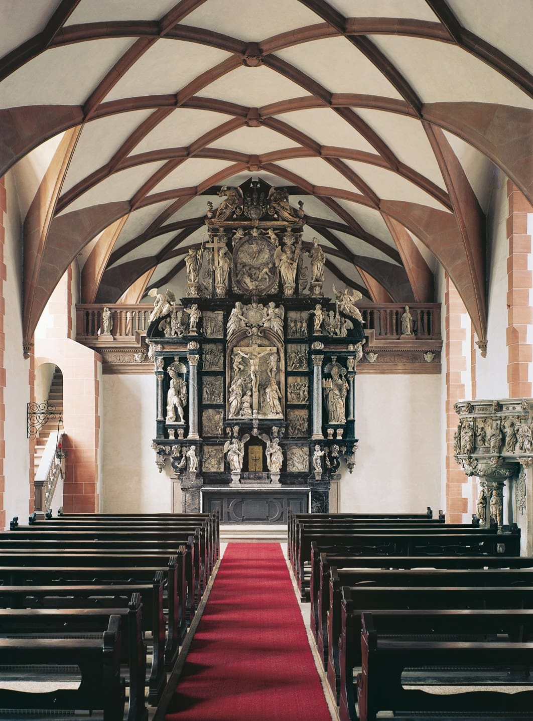 Johannisburg Palace 4 Interior of the Schlosskapelle showing a tall multi-tiered Renaissance high altar with sculpted figures, beneath a ribbed net-vault ceiling.