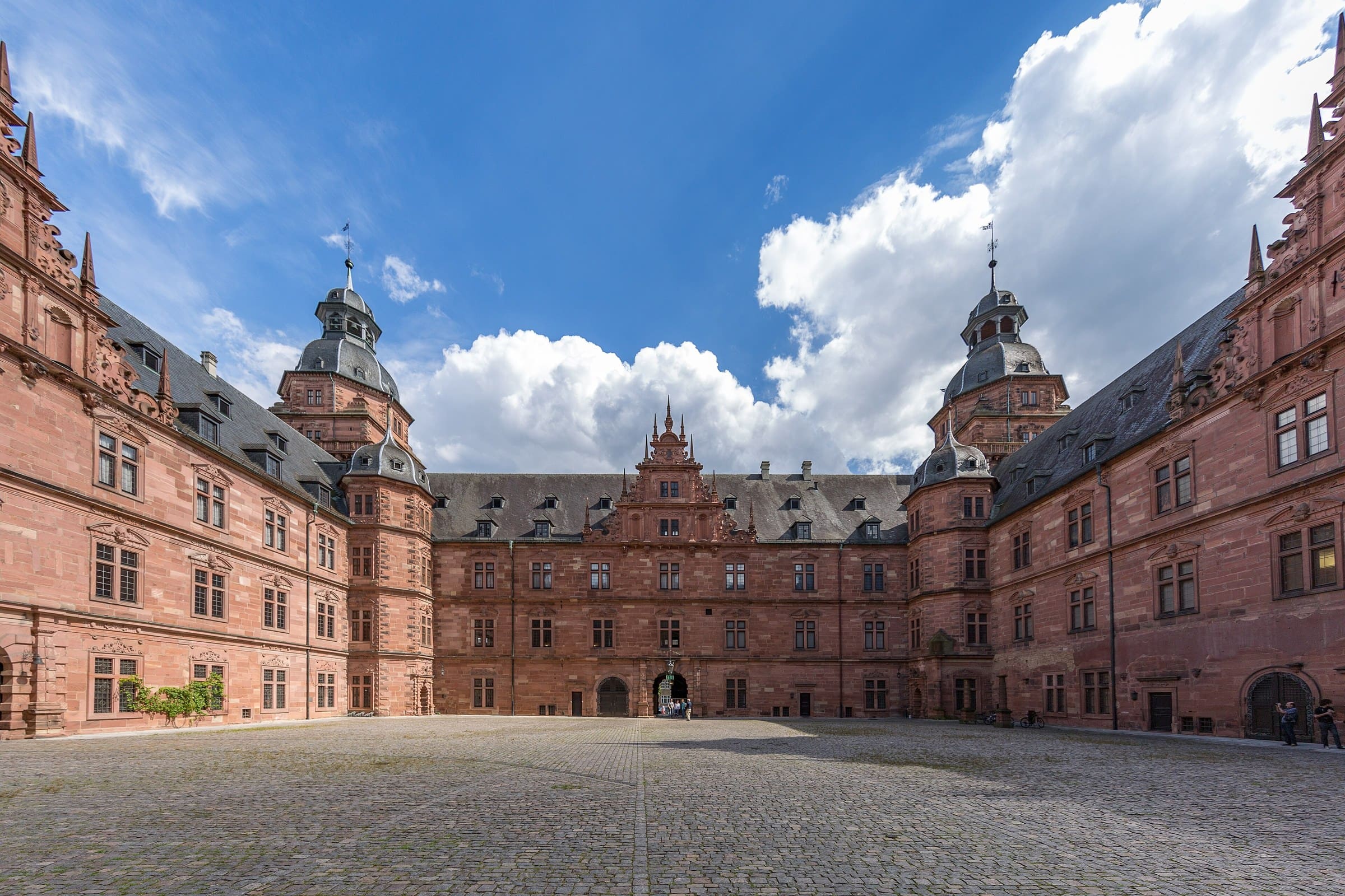 Johannisburg Palace 3 Interior courtyard of Schloss Johannisburg showing three corner towers, red sandstone walls, ornamental gables, and cobblestone paving.