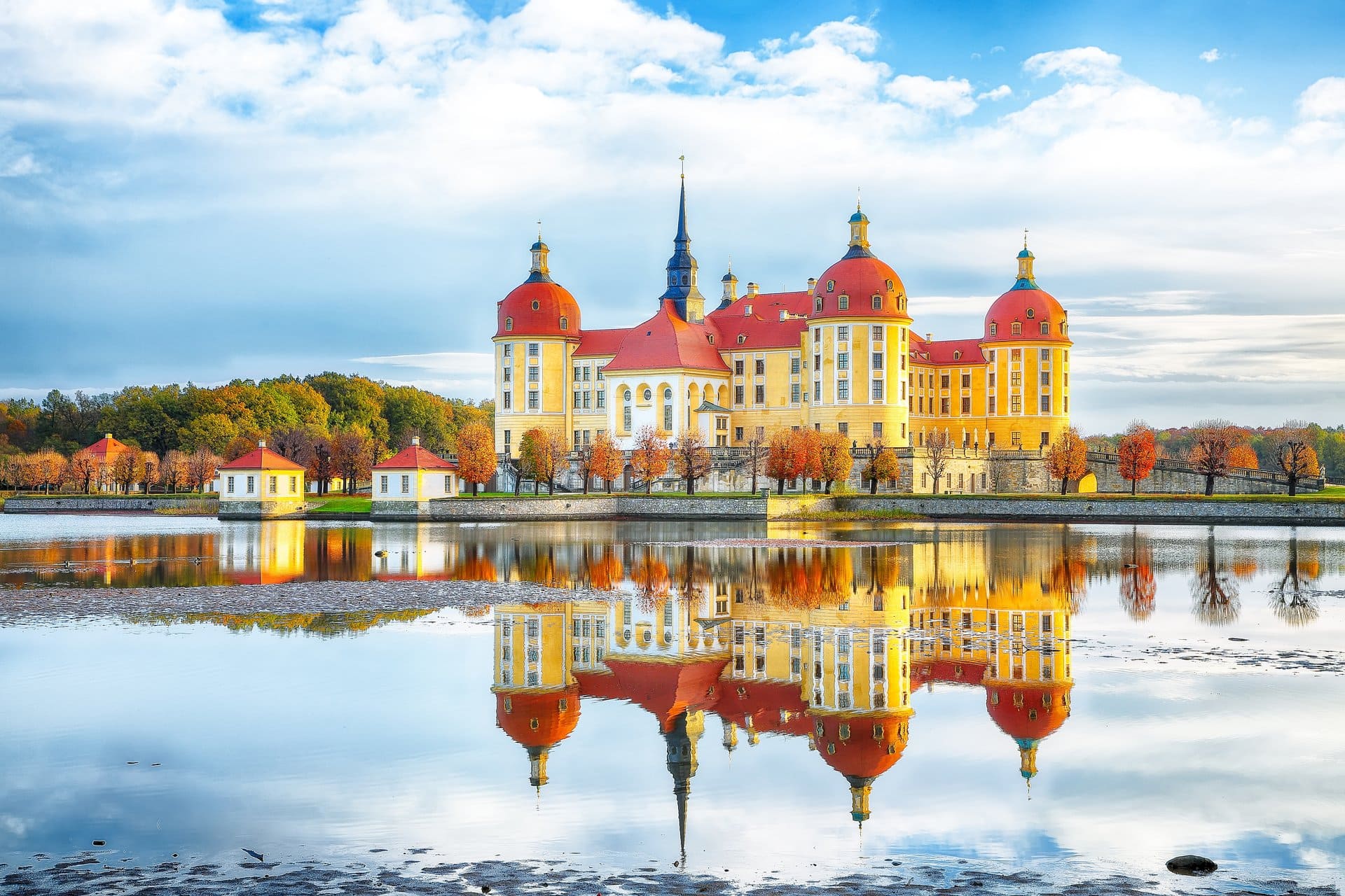 Moritzburg Castle 9 Moritzburg Castle at golden hour in winter, glowing yellow over a frozen pond, with snow on the red domes and silver birch trees in the foreground