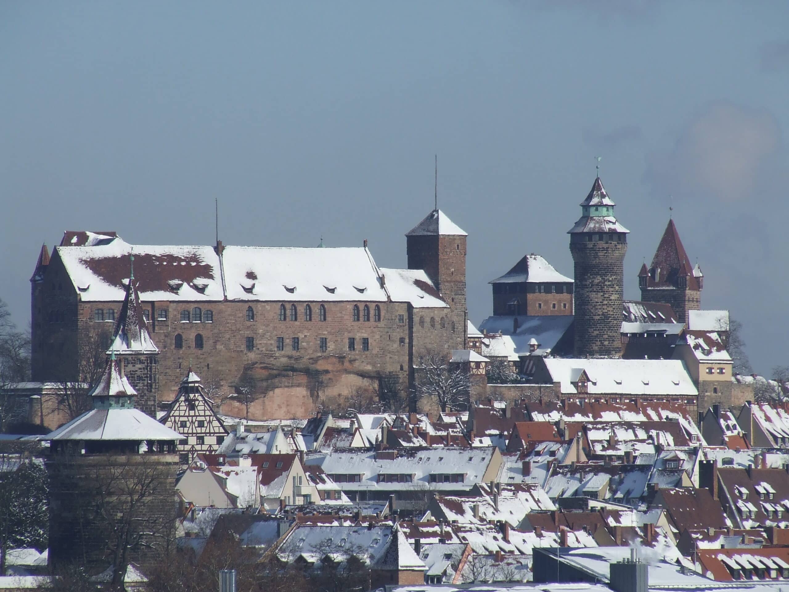 Best Castles in Bavaria 7 The Nuremberg Castle complex viewed from the southwest in winter, with the Palas, Heidenturm, Sinwellturm and Walpurgiskapelle rising above the snow-covered roofs of Nuremberg's Old Town.
