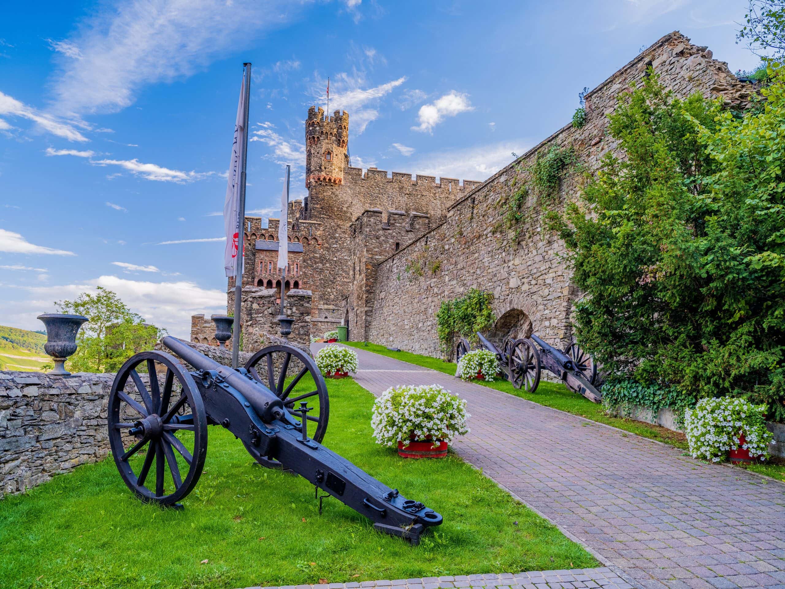 The 19th-Century Romantic Revival of German Castles 12 The entrance to Burg Reichenstein, flanked by historic cannons under a Schildmauer gate, with a massive crenellated tower above.