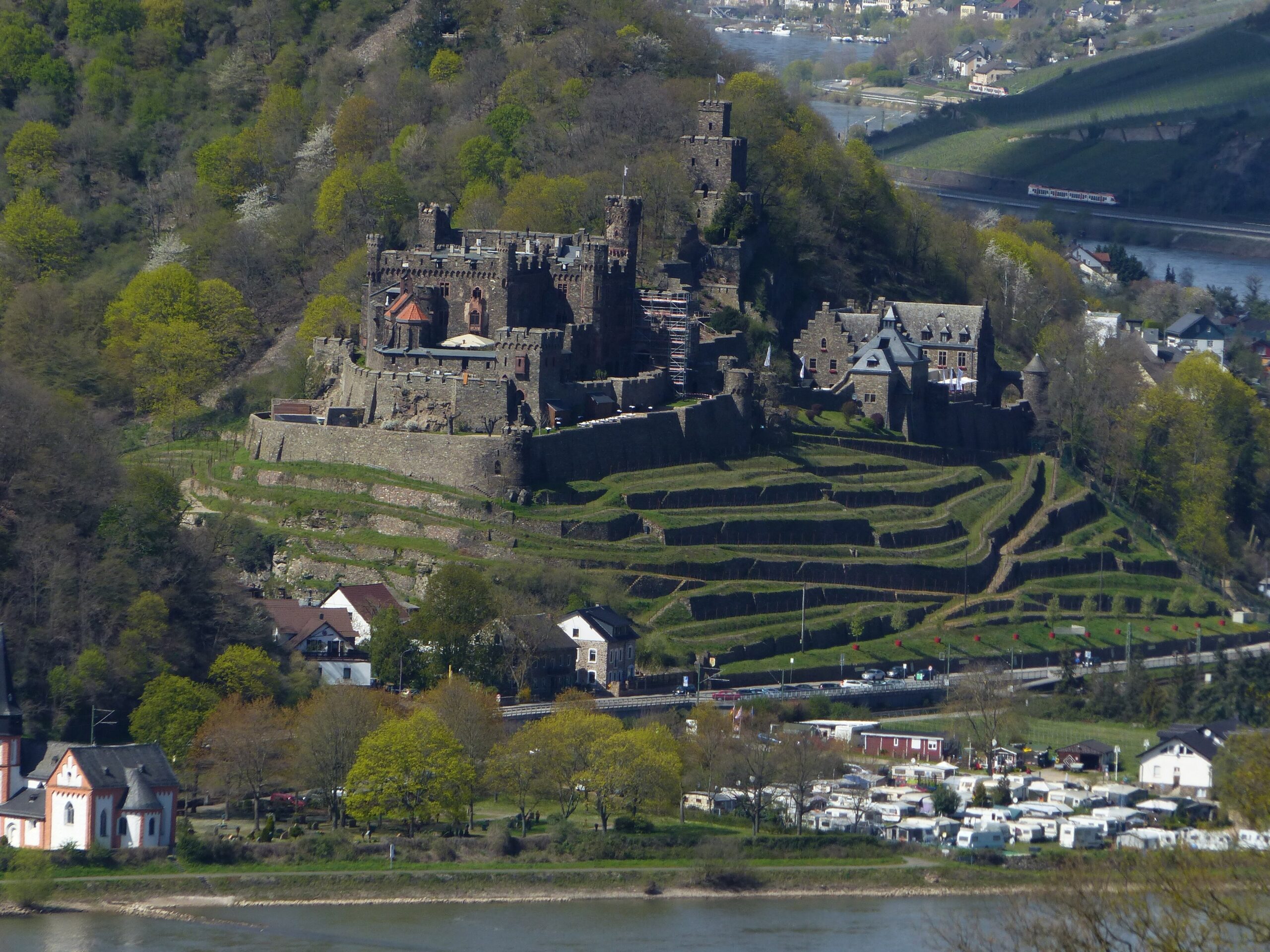 Reichenstein Castle 1 Reichenstein Castle, also known as Falkenburg, on a rocky spur above Trechtingshausen on the left bank of the Rhine, with the Belvedere tower upper right and the outer ring wall and terraced vineyards in the foreground.