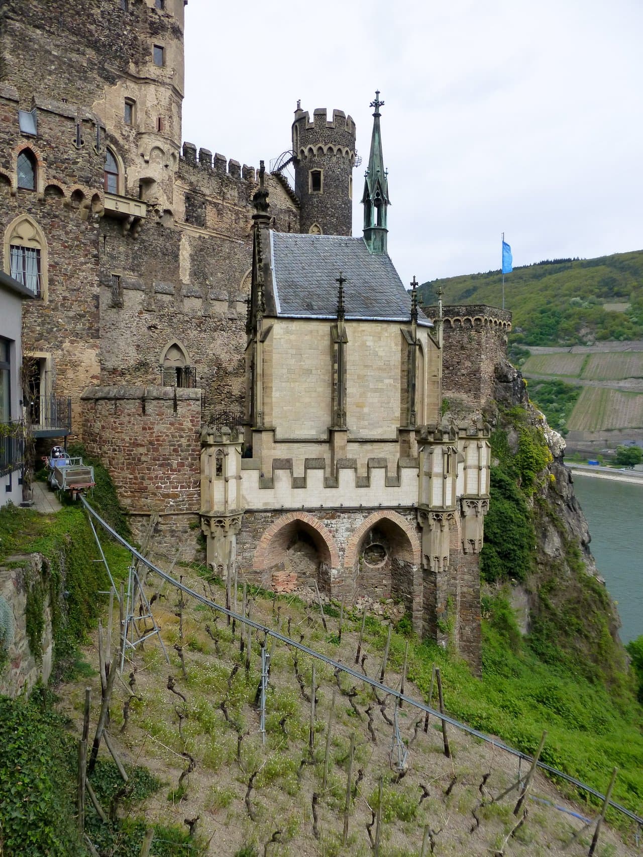Rheinstein Castle 5 The neo-Gothic chapel of Rheinstein Castle seen from the side, with buttresses, pinnacles, and the copper-clad ridge turret rising above a vineyard slope.