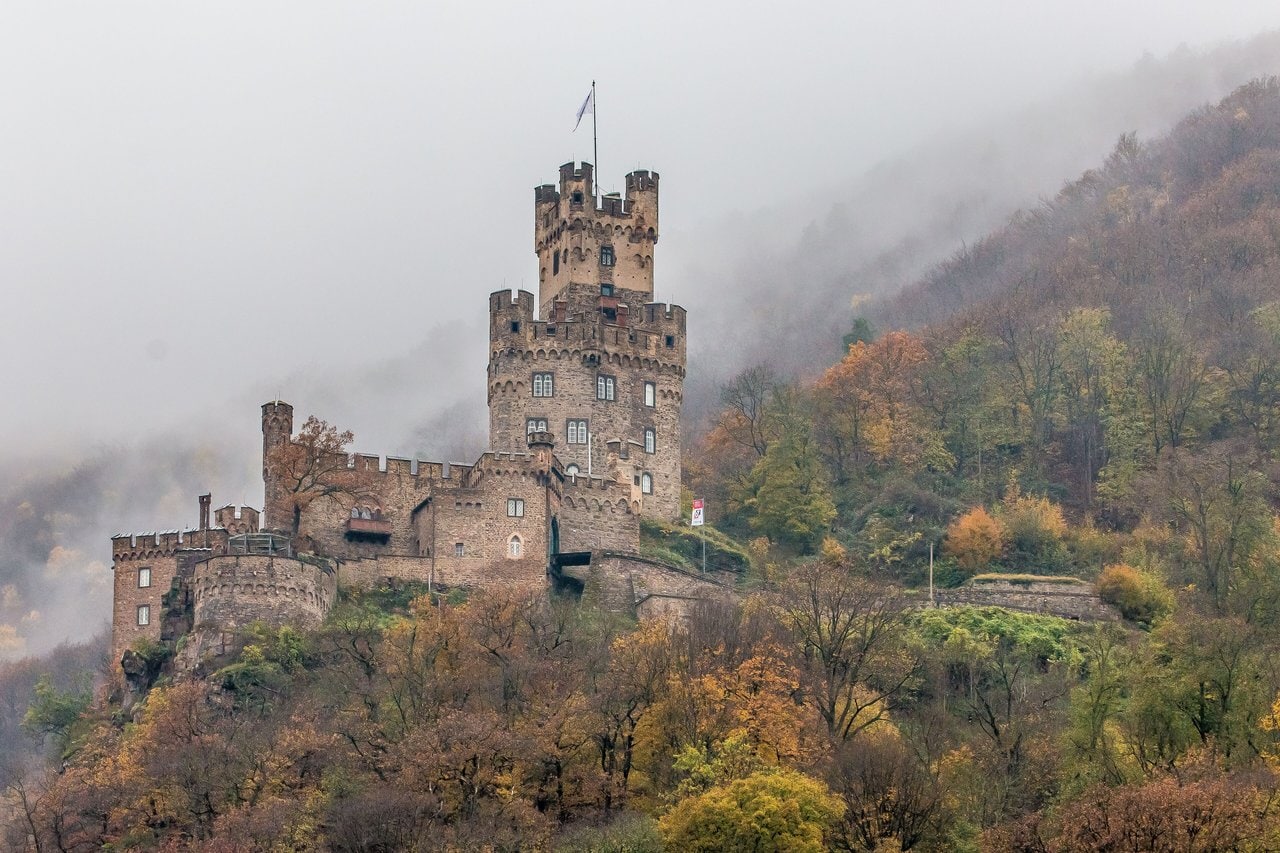 Sooneck Castle 4 Sooneck Castle in late autumn mist, with golden foliage in the foreground and the square Bergfried and Wohnbau emerging from the fog above the Rhine valley.