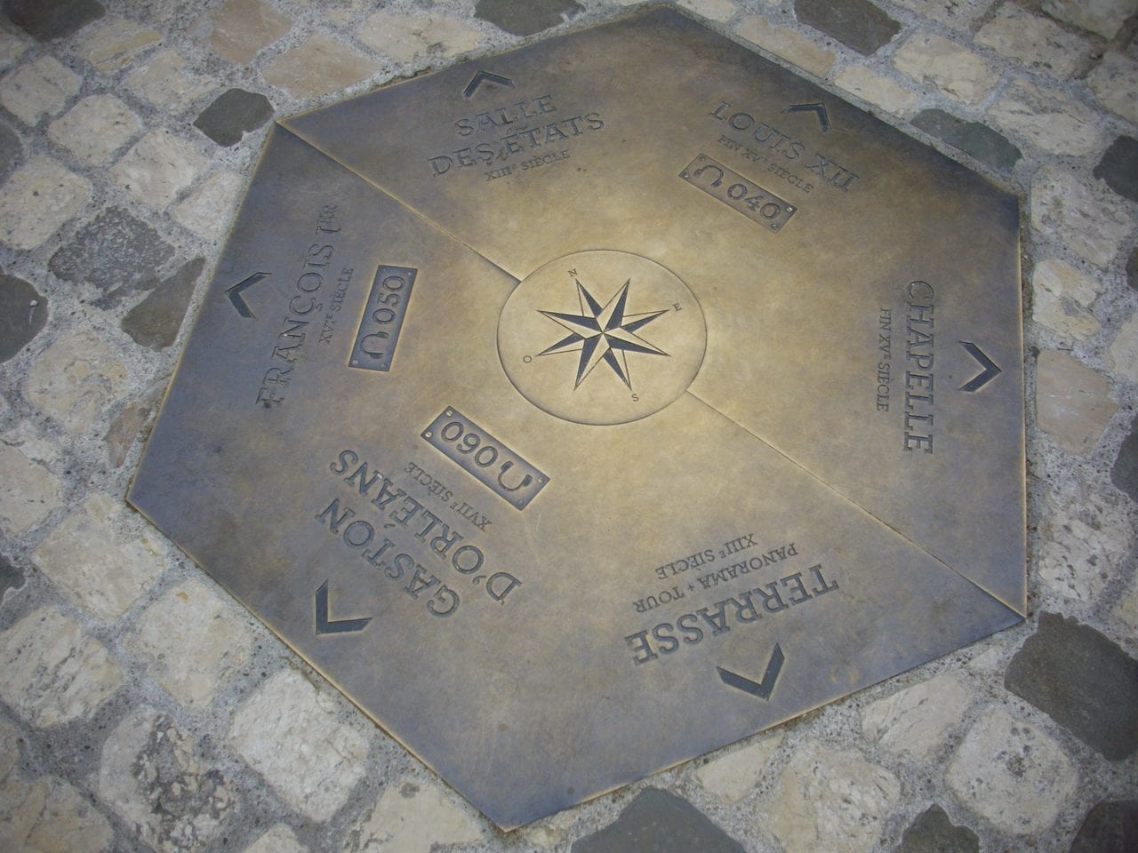 Fab5669, CC BY-SA 4.0, via Wikimedia Commons Bronze orientation plaque in the courtyard pointing to each wing of Château de Blois