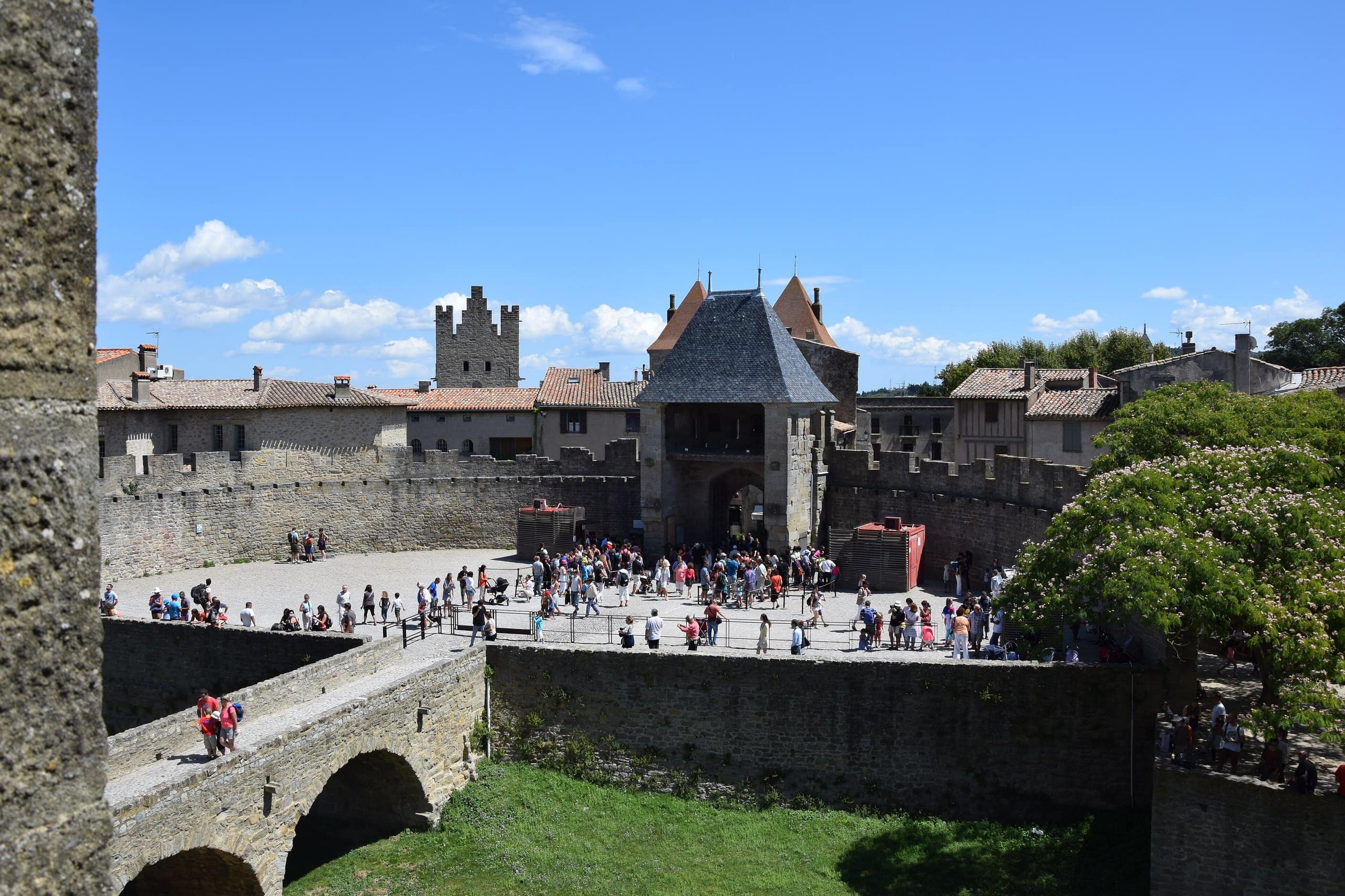 Visitors at the bridge to the Château Comtal — Tournasol7, CC BY-SA 3.0 Visitors crossing the bridge to the Château Comtal of Carcassonne