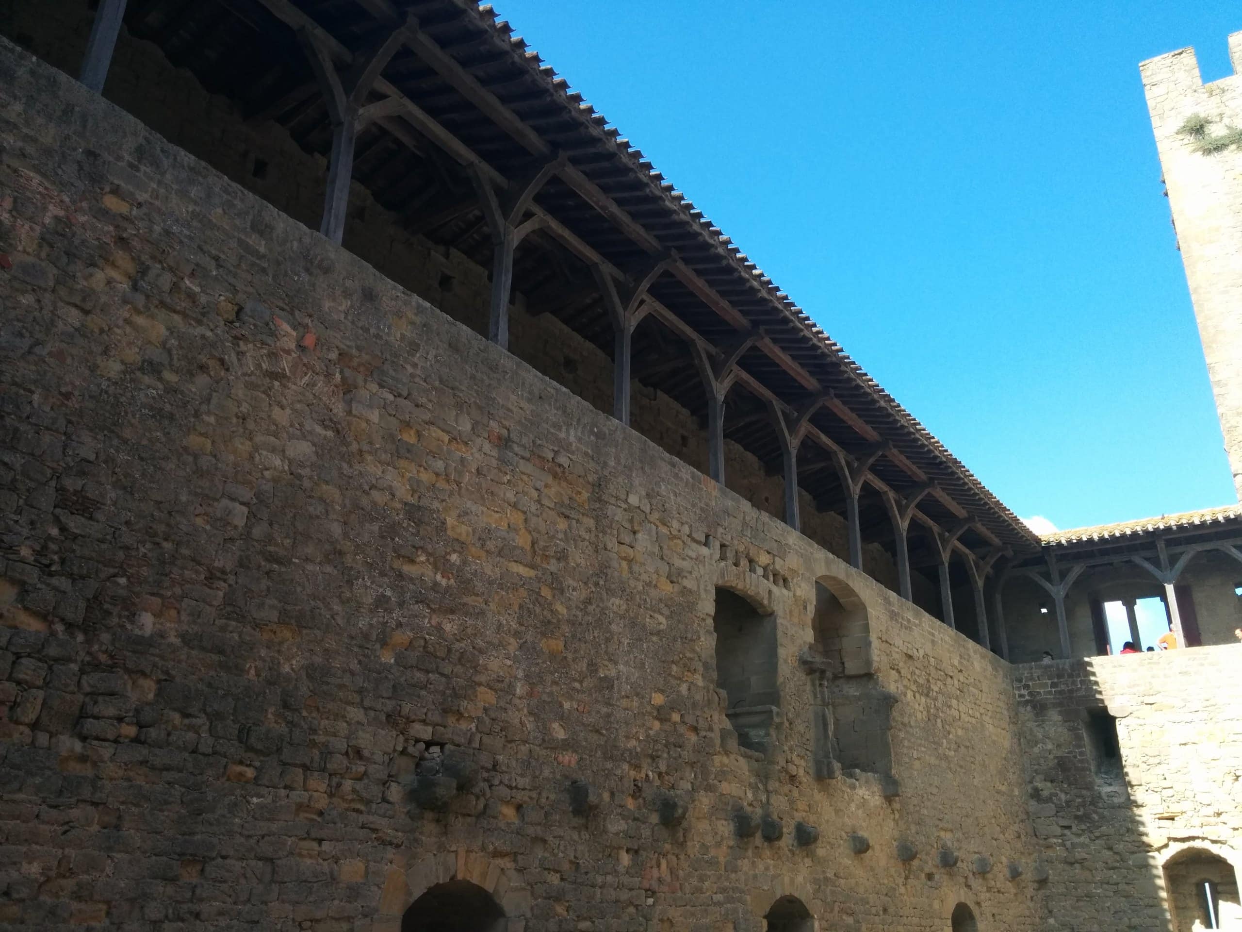 A reconstructed timber hoarding on the wall — Inferno986return, CC BY-SA 4.0 A reconstructed timber hoarding gallery along a wall of the Château Comtal