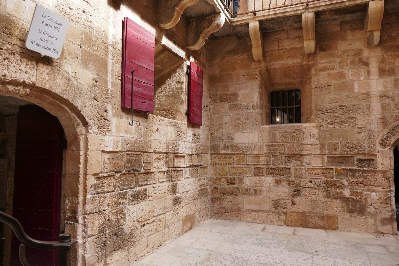 Red shutters and a memorial plaque marking Gaston Crémieux's cell at Château d'If.