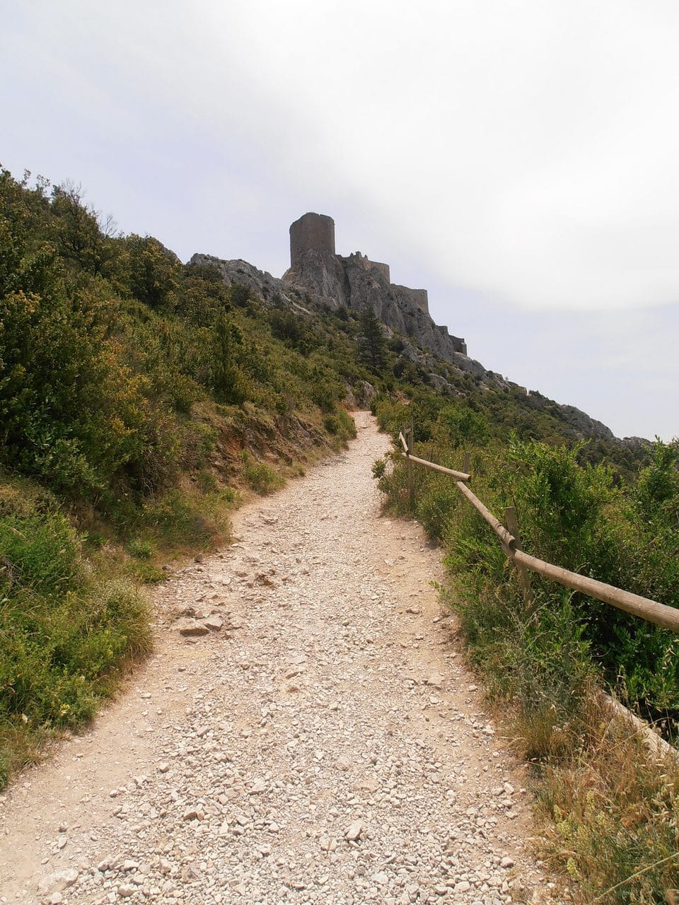 Footpath climbing toward Château de Quéribus with a wooden handrail