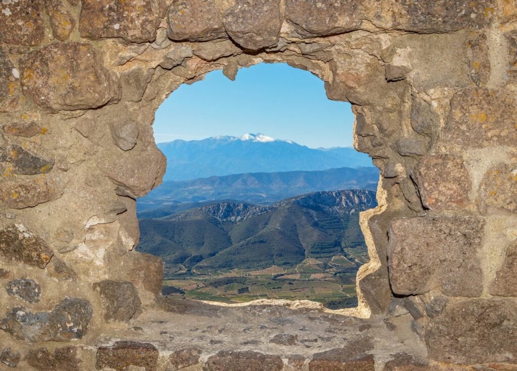 A castle window at Quéribus framing the distant peak of the Canigou