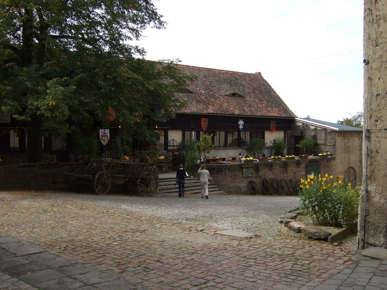 The Burgschänke courtyard — Sebastian Wallroth, public domain, via Wikimedia Commons The Burgschaenke courtyard at Leuchtenburg Castle with its half-timbered tavern building and old hay wagon