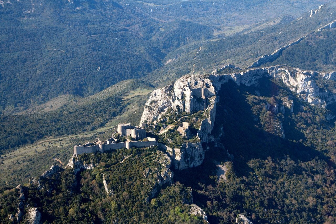 Aerial view of the whole fortress — Rémi Guillot, CC BY-SA 4.0 Aerial view of Château de Peyrepertuse strung along its mountain crest