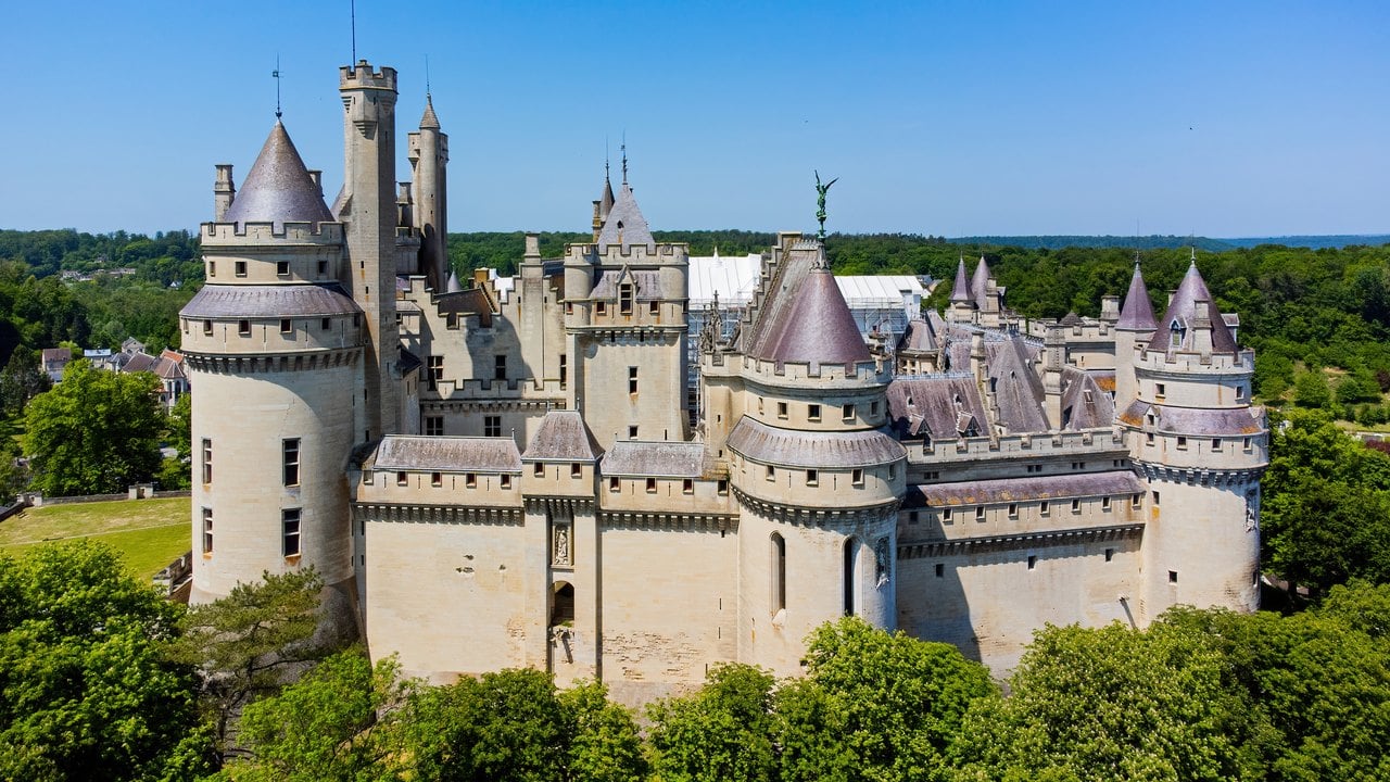 Château de Pierrefonds 1 Aerial view of Château de Pierrefonds, its ring of round towers and conical roofs rising above the Forest of Compiègne