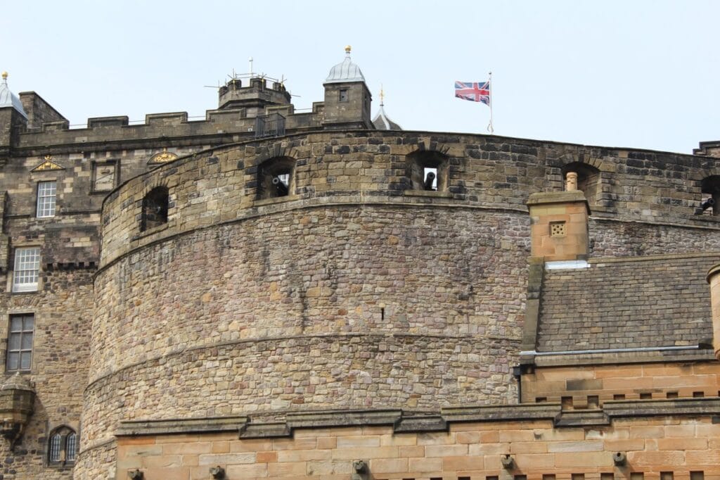 Edinburgh Castle 6 The curved wall of the Half Moon Battery, gunports ranged along its face and the Union flag flying above the ramparts.