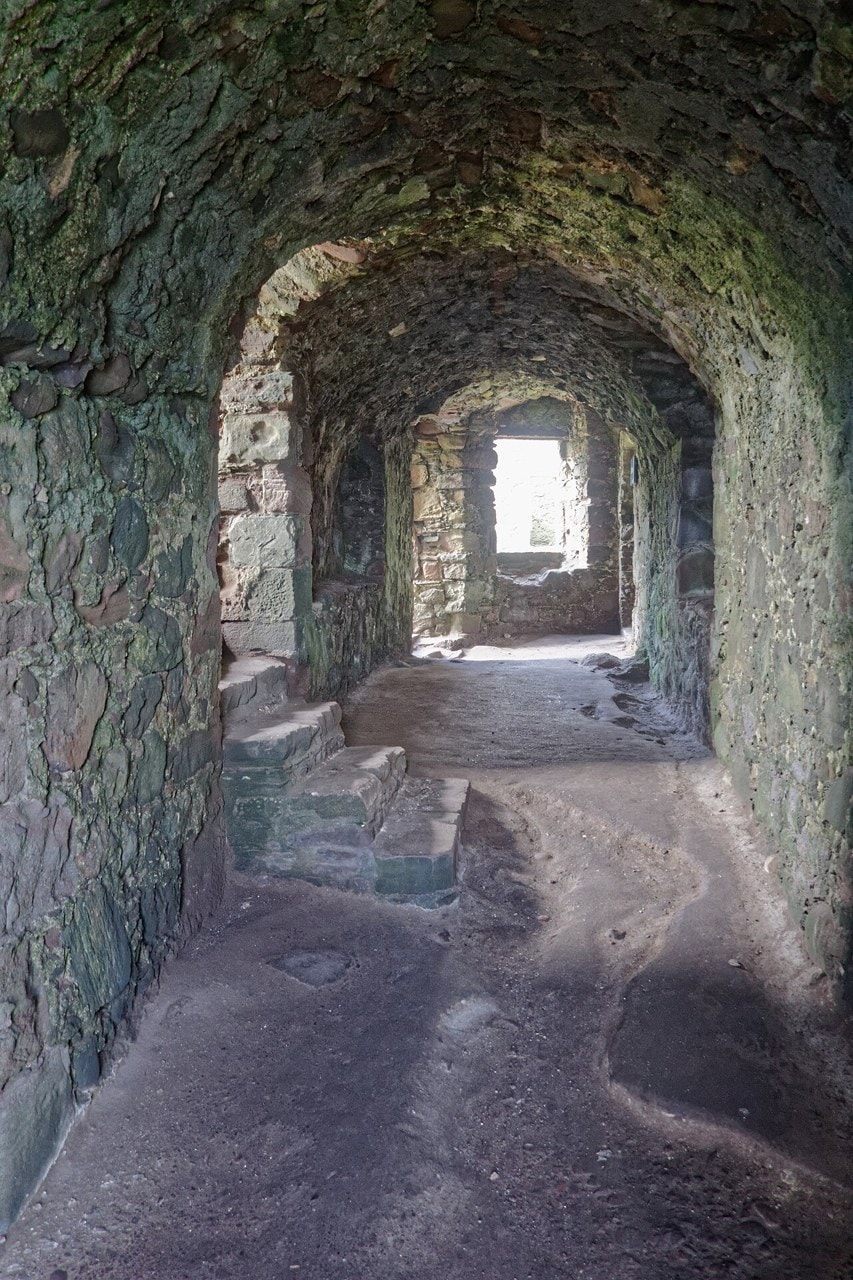 Interior of a barrel-vaulted stone cellar at Dunnottar Castle with arched recesses and a lit window opening. Interior of a barrel-vaulted stone cellar at Dunnottar Castle with arched recesses and a lit window opening.