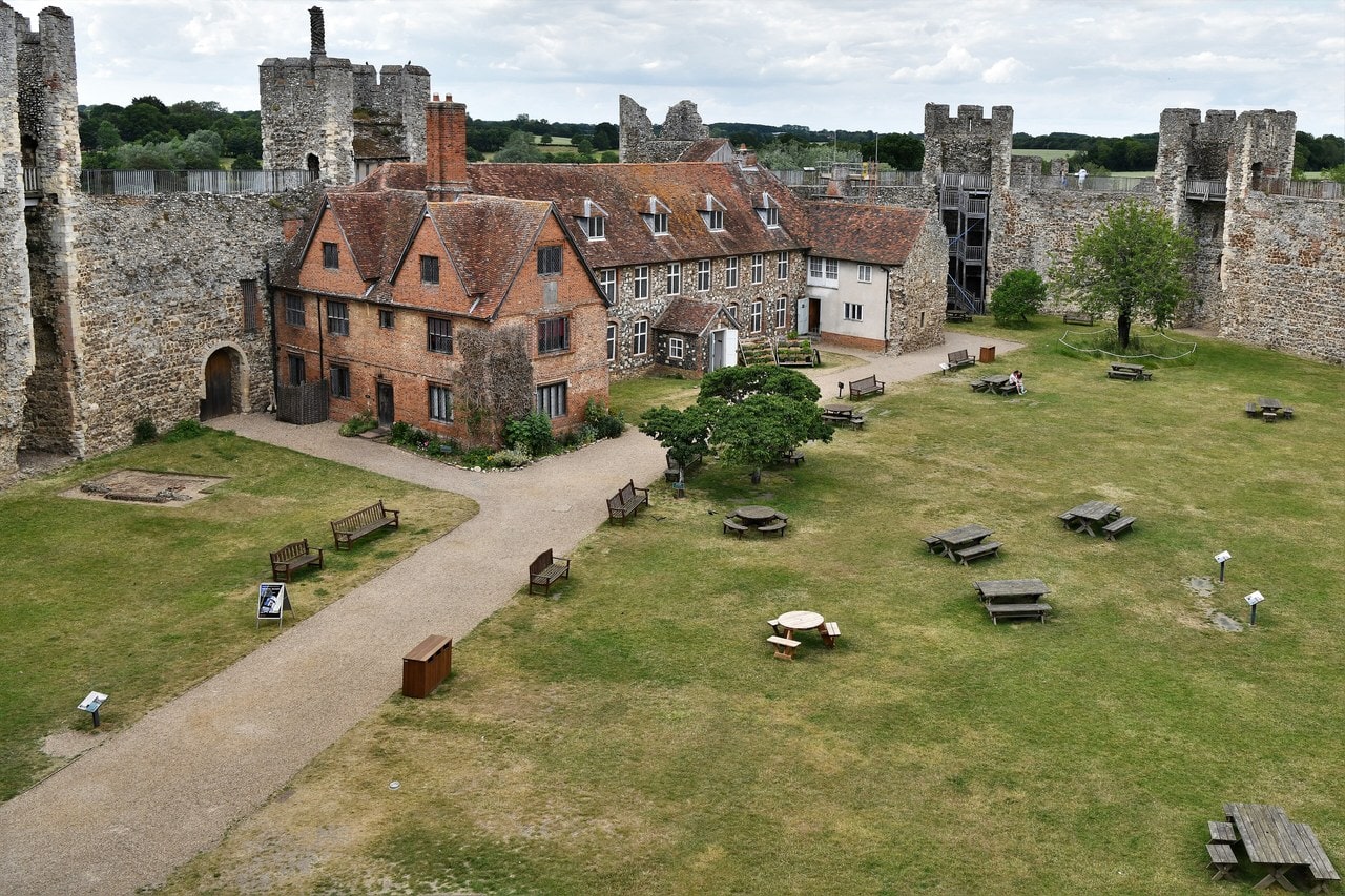 View from the wall-walk down into the grassy inner court of Framlingham Castle, ringed by a stone curtain wall with square towers. View from the wall-walk down into the grassy inner court of Framlingham Castle, ringed by a stone curtain wall with square towers.