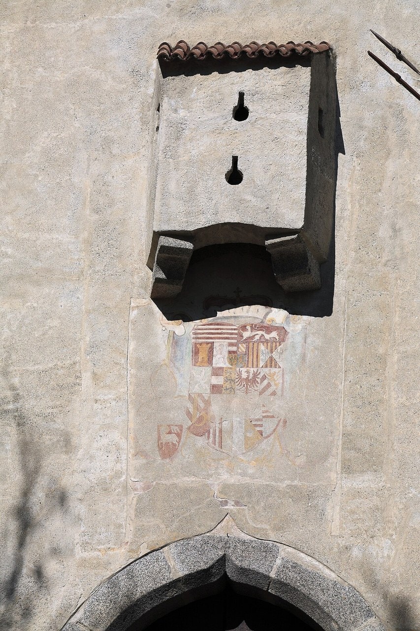 A small roofed stone box projecting on two corbels from a wall directly above a pointed-arch gateway at Schloss Bruneck, with an open slot visible in the underside of the box. A small roofed stone box projecting on two corbels from a wall directly above a pointed-arch gateway at Schloss Bruneck, with an open slot visible in the underside of the box.