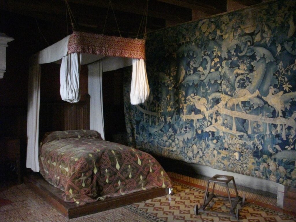 Château de Langeais 6 A canopied bed set against a mille-fleurs tapestry in the furnished rooms. Photo: Fab5669, CC BY-SA 4.0, via Wikimedia Commons.