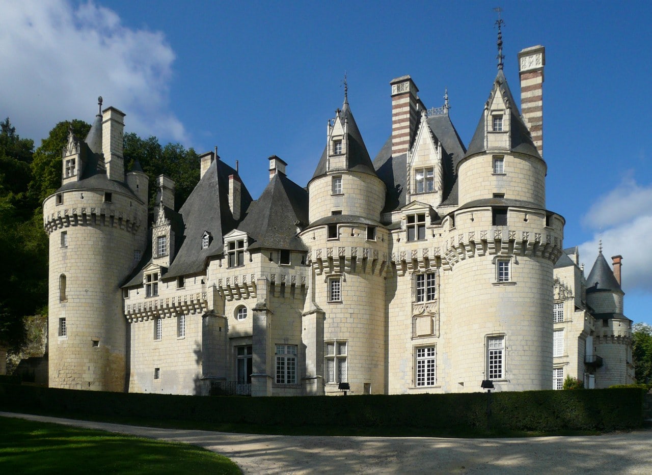 Cluster of white-tufa round turrets with conical slate roofs and striped brick chimneys at Château d'Ussé, seen from the forecourt against a blue sky. Cluster of white-tufa round turrets with conical slate roofs and striped brick chimneys at Château d'Ussé, seen from the forecourt against a blue sky.