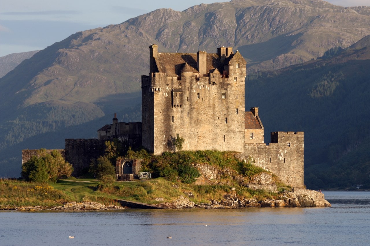 Evening light warms the rebuilt tower house as it mirrors in the still water of Loch Duich. Evening light warms the rebuilt tower house as it mirrors in the still water of Loch Duich.