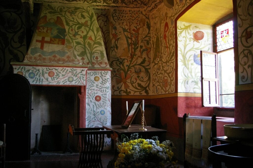 A frescoed residential chamber at Burg Eltz with a painted hooded fireplace and floral wall paintings