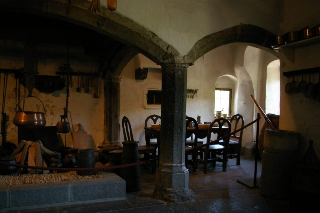 The vaulted medieval kitchen at Burg Eltz with a central pillar and a copper cauldron by the hearth