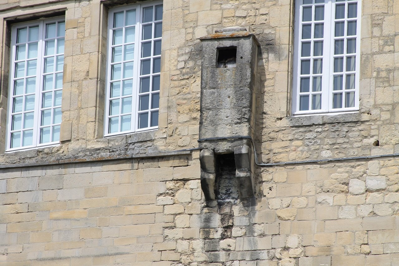 A corbelled stone latrine chute projecting from a castle wall at Caen, with a seat opening at the top and a stained discharge at its base. A corbelled stone latrine chute projecting from a castle wall at Caen, with a seat opening at the top and a stained discharge at its base.