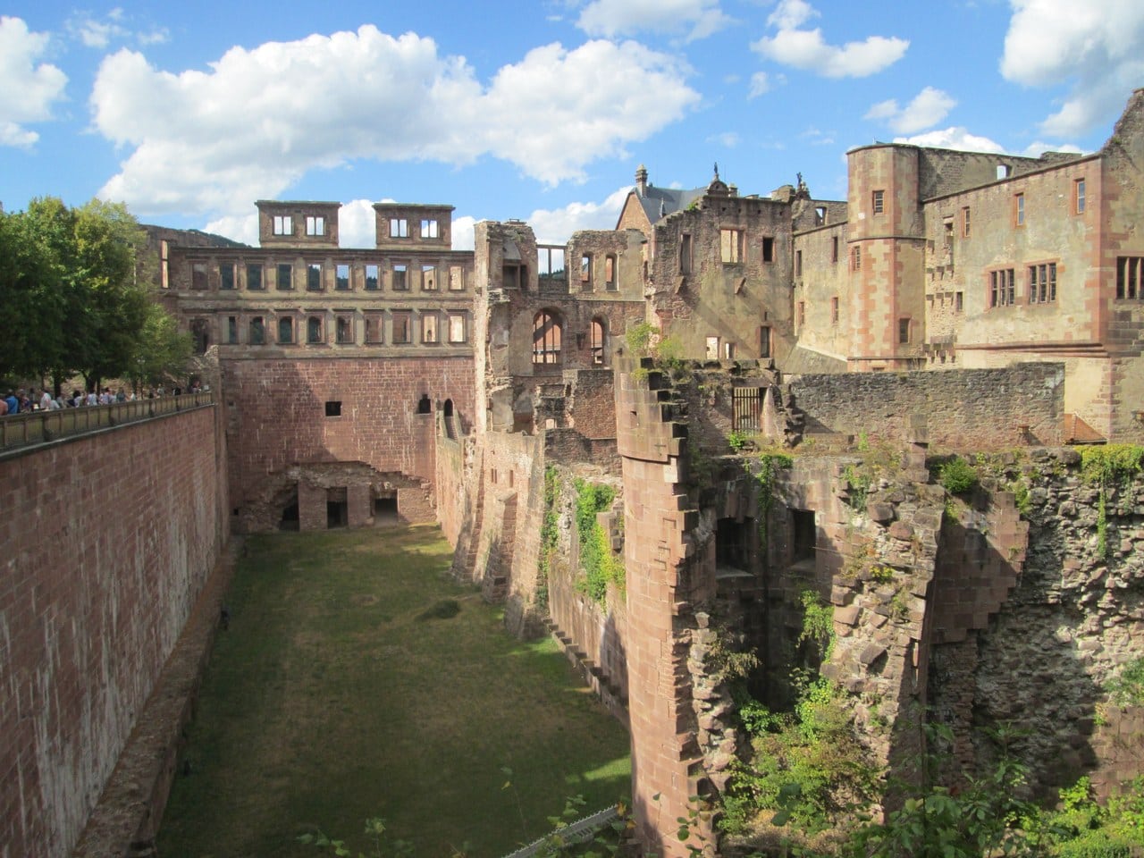 The broad grassed dry ditch on the west side of Heidelberg Castle, with the ruined palace ranges rising above the scarp and a visitor path along the counterscarp The broad grassed dry ditch on the west side of Heidelberg Castle, with the ruined palace ranges rising above the scarp and a visitor path along the counterscarp
