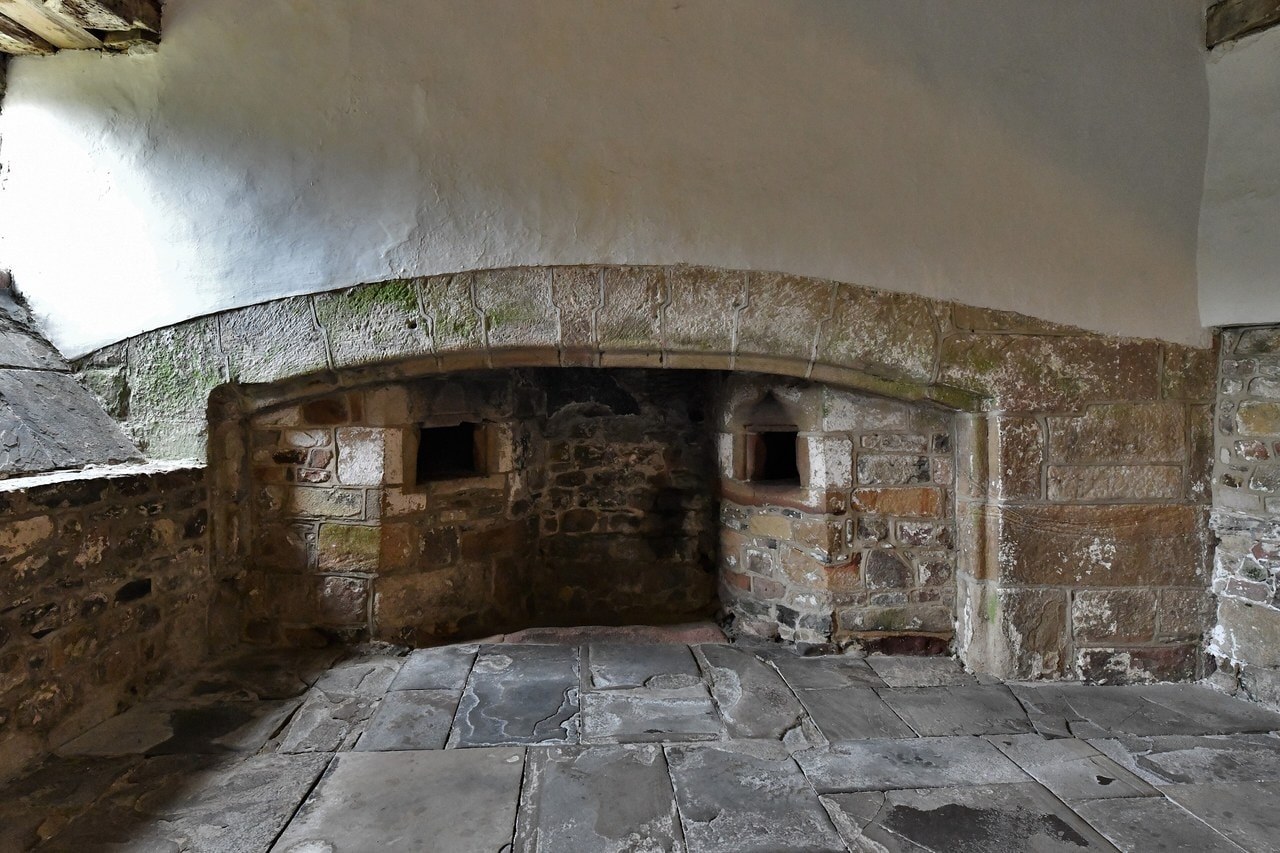 The medieval kitchen at Skipton Castle: a wide stone fireplace under a low vault, with a small arched baking oven set into each flank. The medieval kitchen at Skipton Castle: a wide stone fireplace under a low vault, with a small arched baking oven set into each flank.