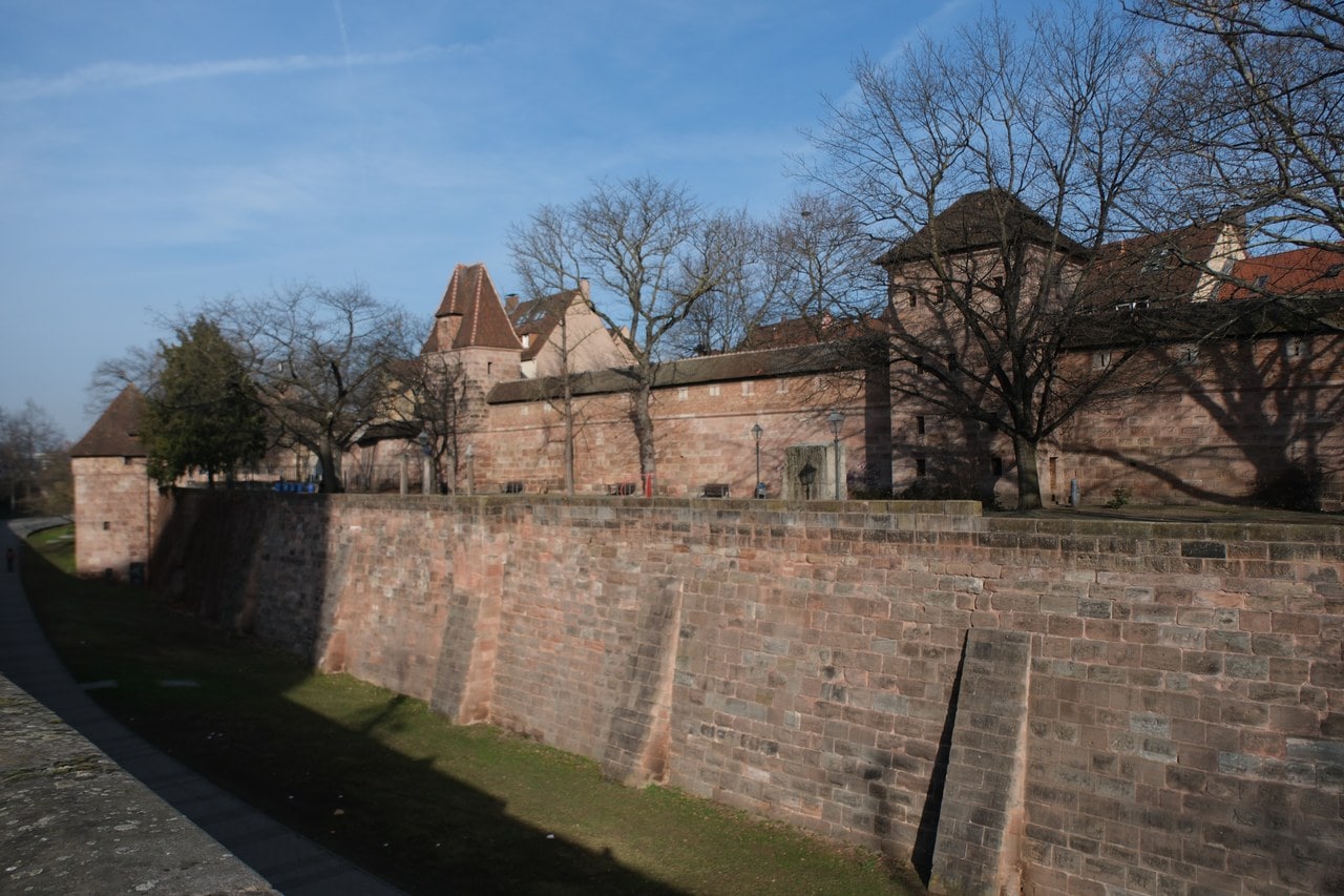 Nuremberg's dry city ditch below the Frauentormauer, a buttressed sandstone retaining wall rising from the grass floor with the city wall and its towers above Nuremberg's dry city ditch below the Frauentormauer, a buttressed sandstone retaining wall rising from the grass floor with the city wall and its towers above