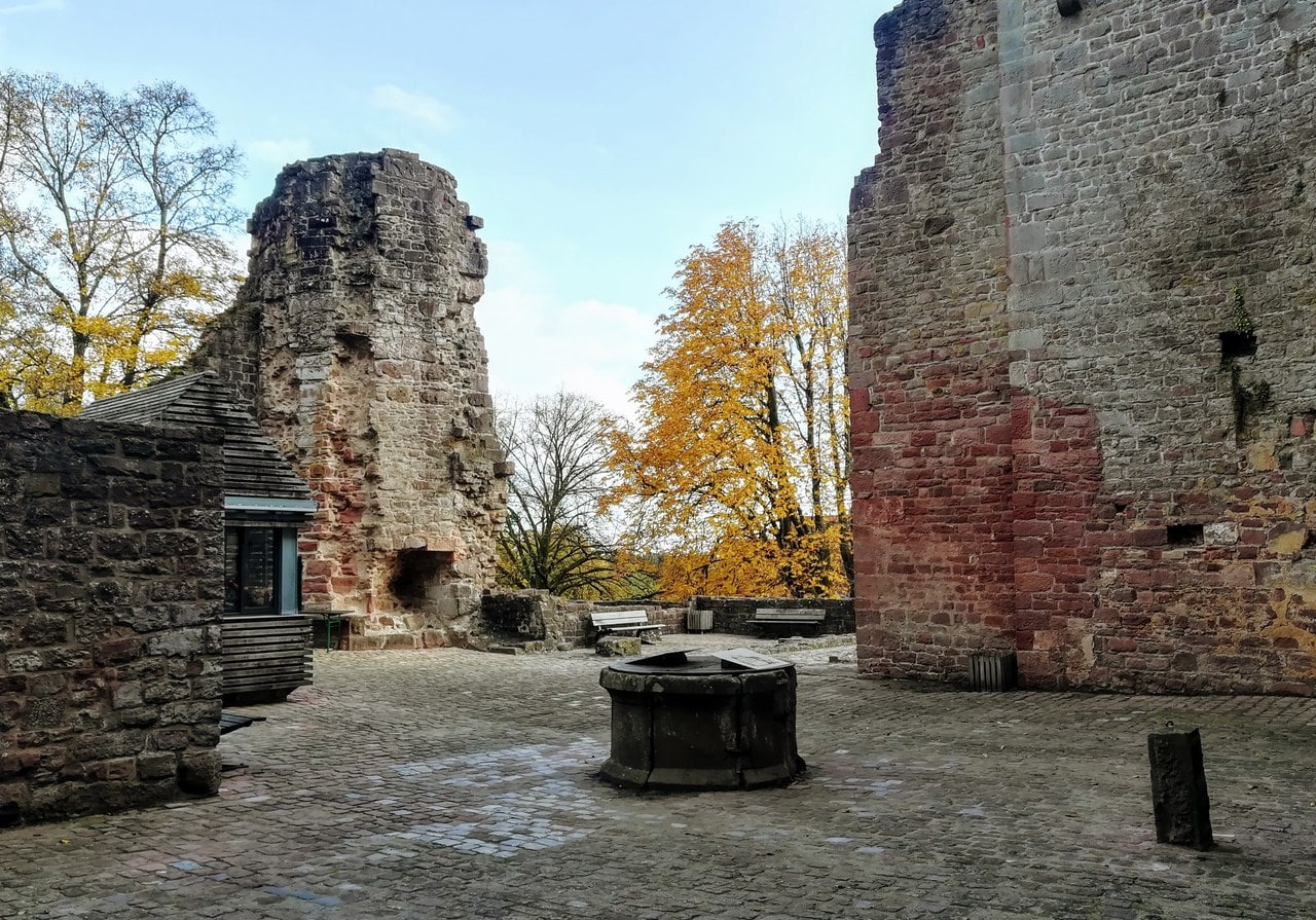 A round stone well head at the center of a cobbled castle courtyard at Dilsberg, between a ruined entrance range and a high mantle wall. A round stone well head at the center of a cobbled castle courtyard at Dilsberg, between a ruined entrance range and a high mantle wall.