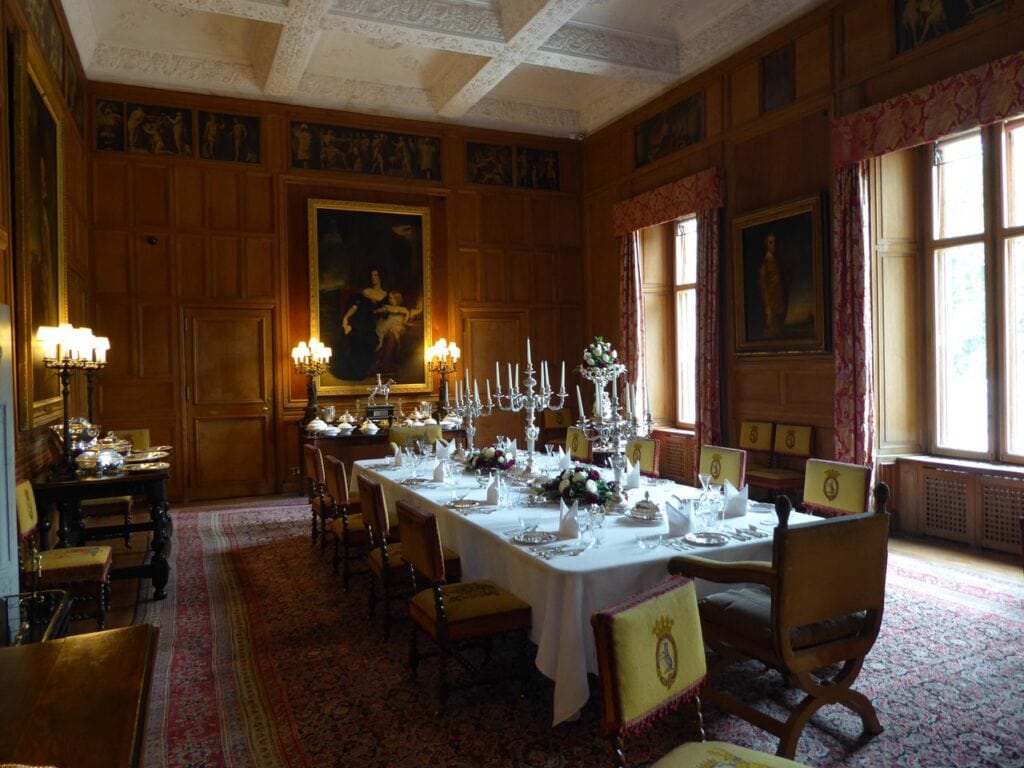 Dunrobin Castle 9 A long dining room with a coffered plaster ceiling and a painted grisaille frieze, a table laid the length of the room and portraits on the panelled walls.
