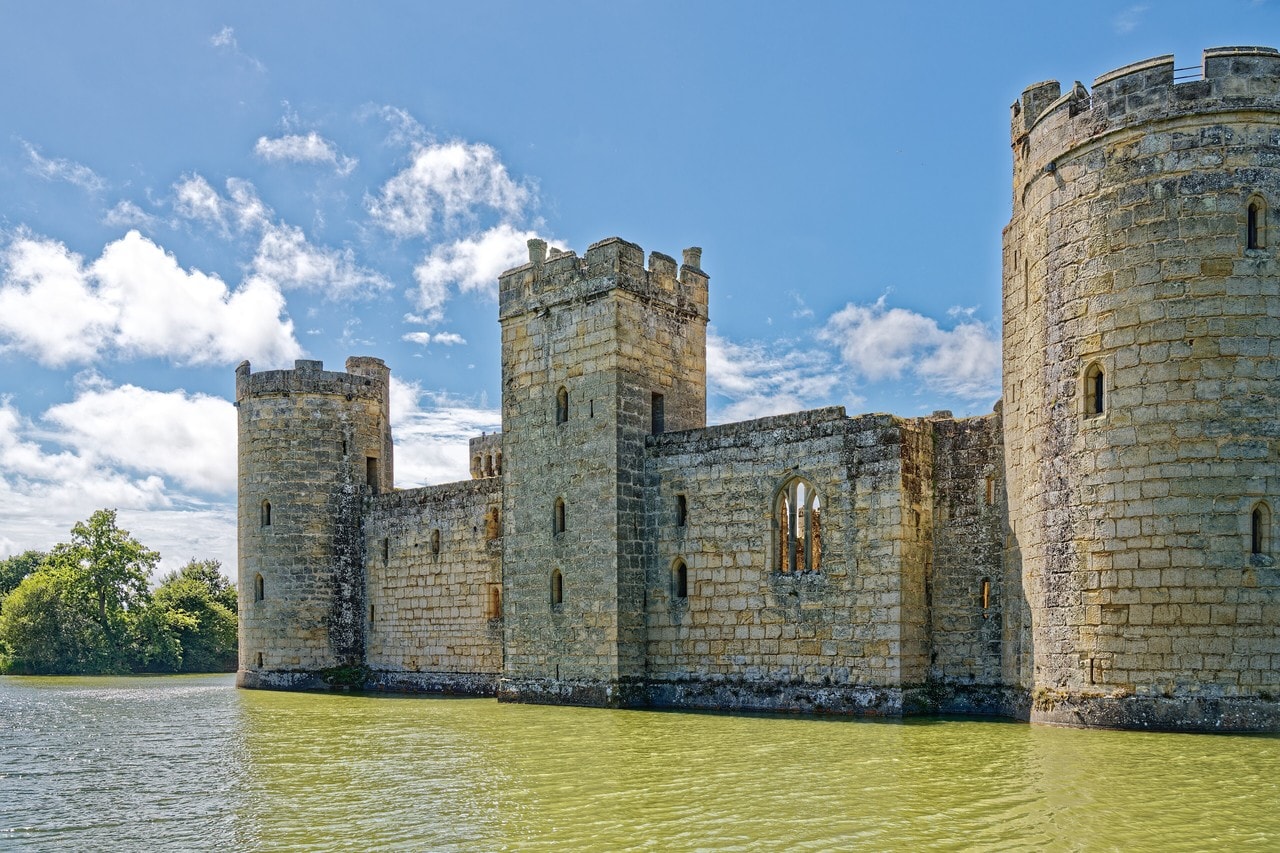 The east wall of Bodiam Castle rising out of its moat, with a square tower projecting from the middle of the curtain and a round drum tower at each end of the wall, all three standing forward of the wall face. The east wall of Bodiam Castle rising out of its moat, with a square tower projecting from the middle of the curtain and a round drum tower at each end of the wall, all three standing forward of the wall face.