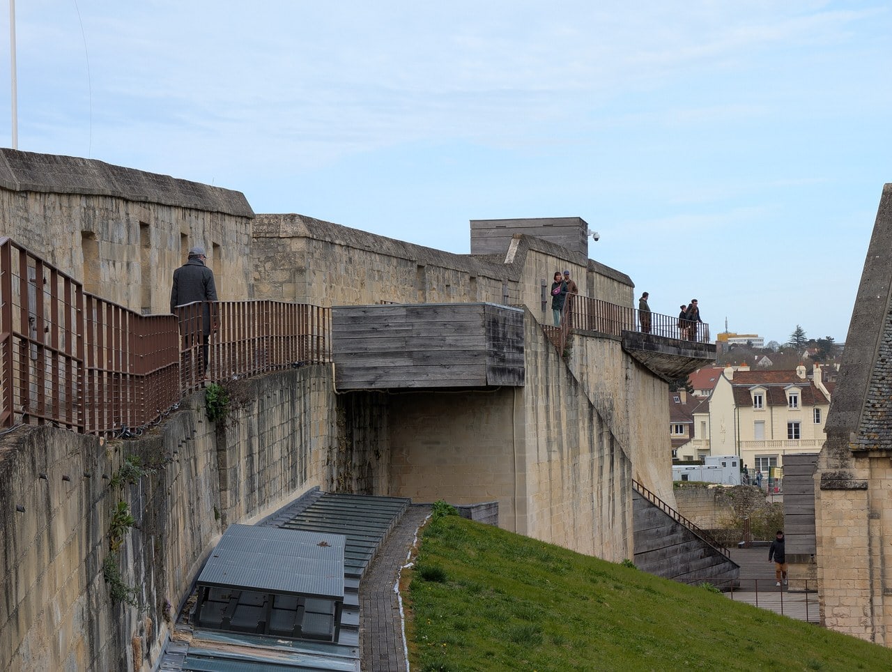 Visitors walking the rampart wall walk at the Château de Caen on a modern timber deck laid along the top of the curtain wall. Visitors walking the rampart wall walk at the Château de Caen on a modern timber deck laid along the top of the curtain wall.