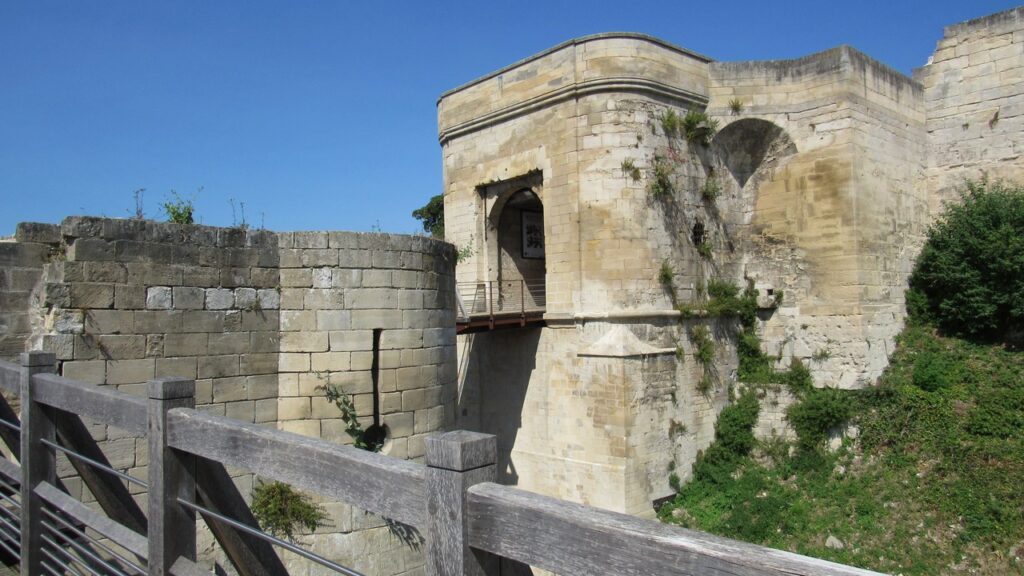 Château de Caen 4 The rounded gate block of the Porte Saint-Pierre at the Château de Caen above a deep ditch, with a round barbican drum in the foreground.