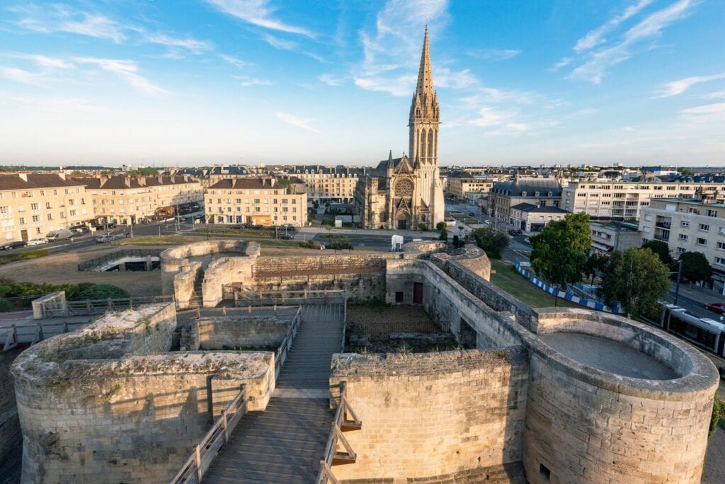 Château de Caen 2 The barbican of the Porte Saint-Pierre seen from the rampart above, with the spire of the church of Saint-Pierre and the roofs of Caen beyond.