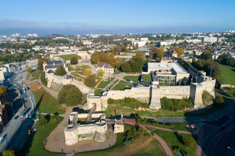 Home 6 Aerial view of the Château de Caen, its curtain wall and towers enclosing a large open bailey with the city of Caen all around.